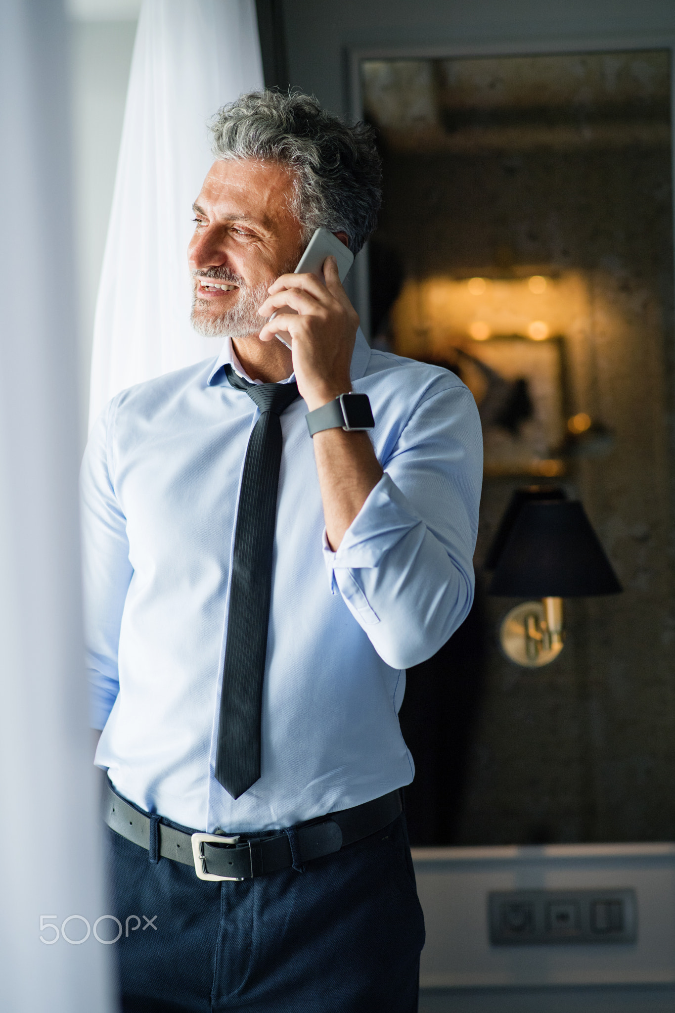 Mature businessman with smartphone in a hotel room.