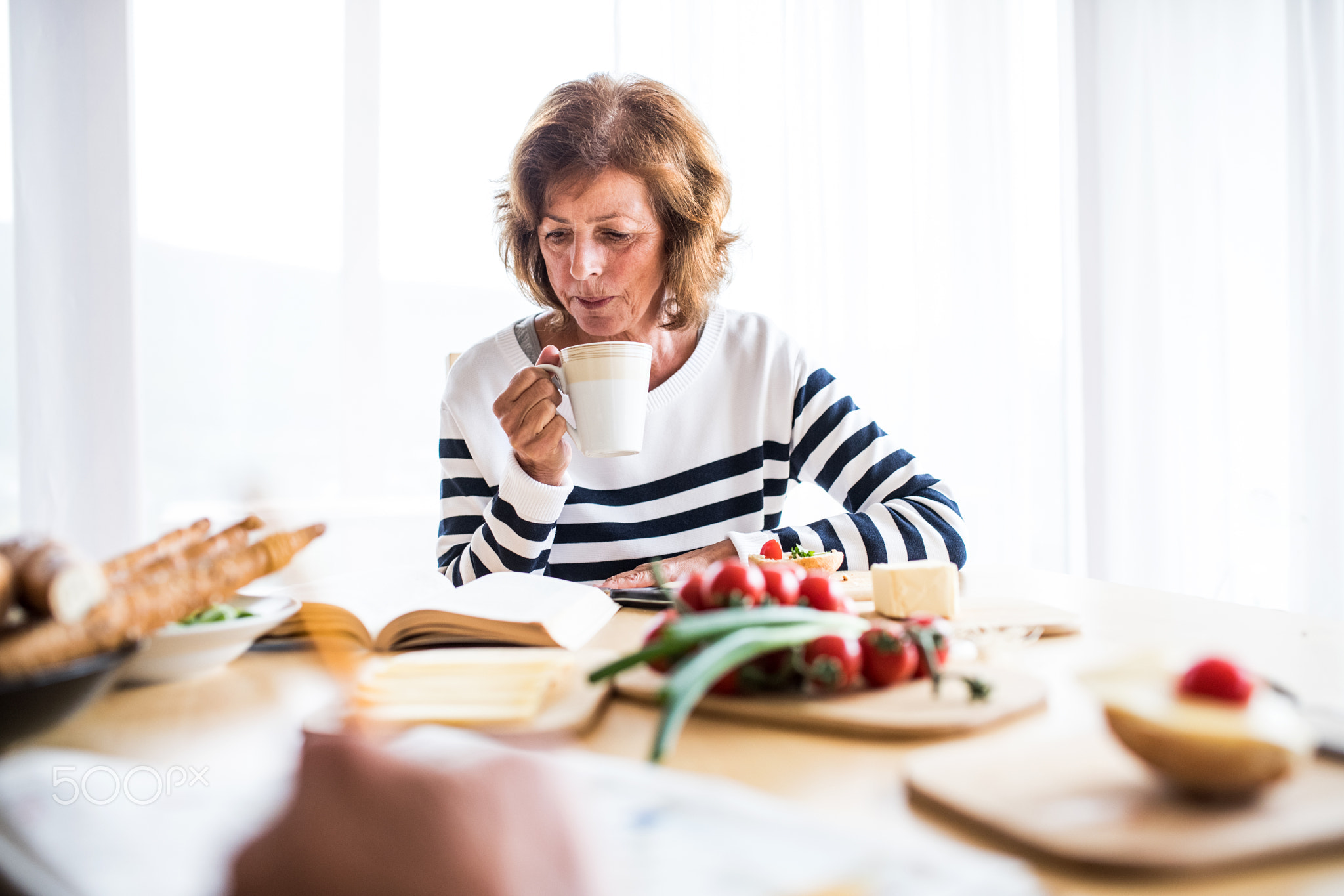 Senior woman eating breakfast at home.