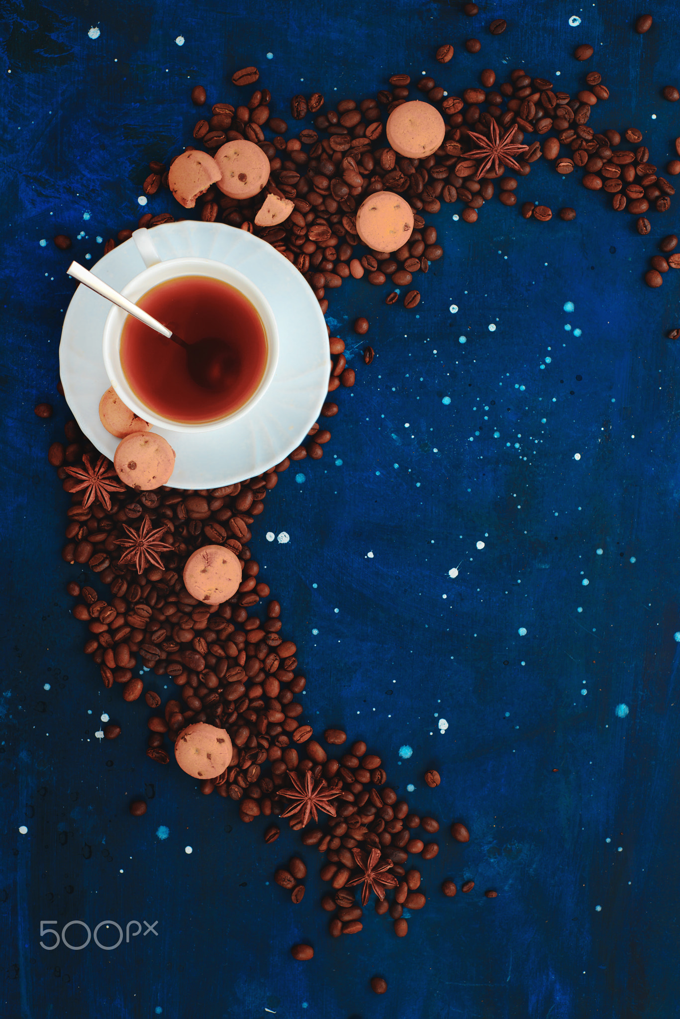 White porcelain coffee cup on a dark background with cinnamon, anise stars, cookies and scattered...