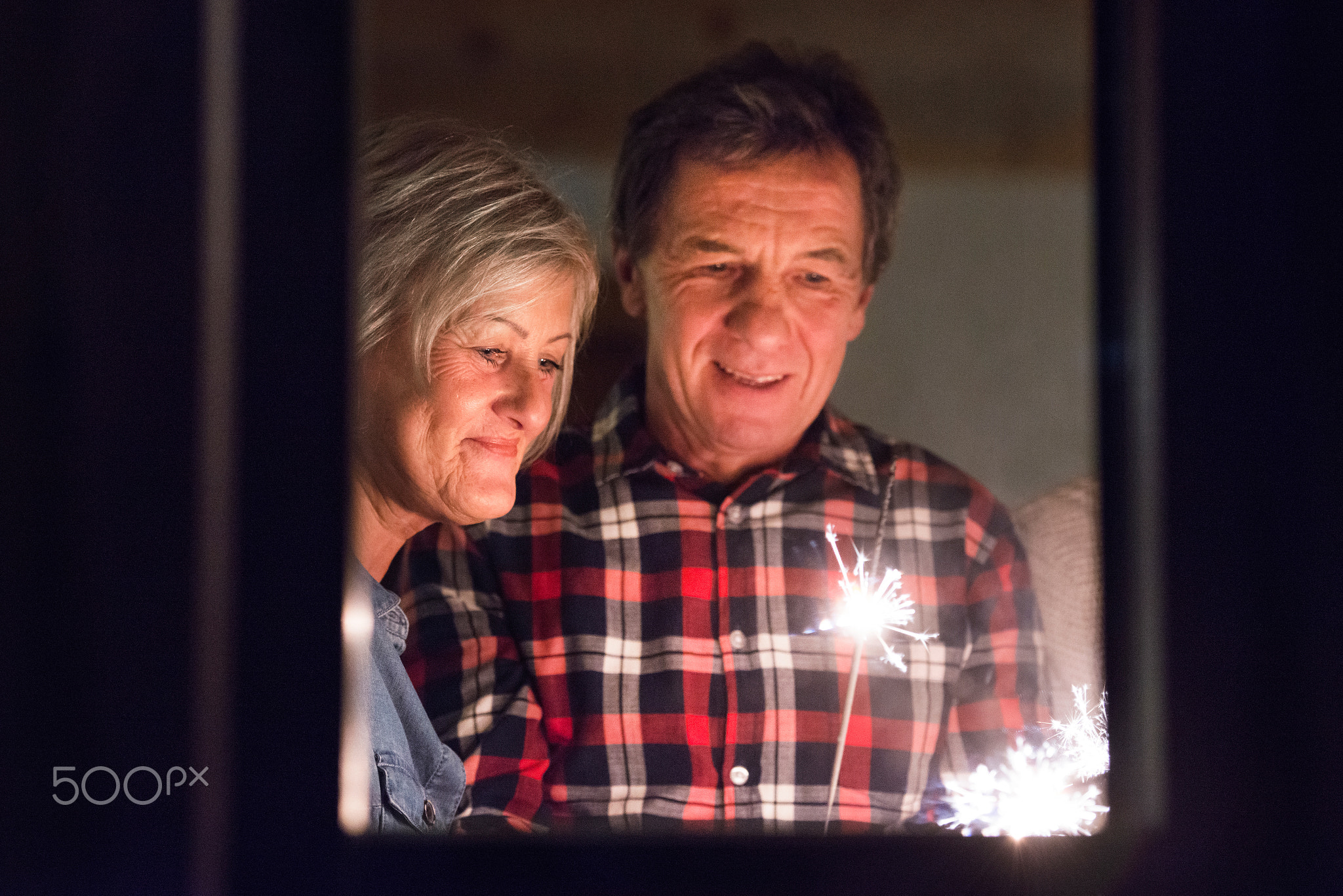 Senior couple with sparklers at Christmas time having fun.