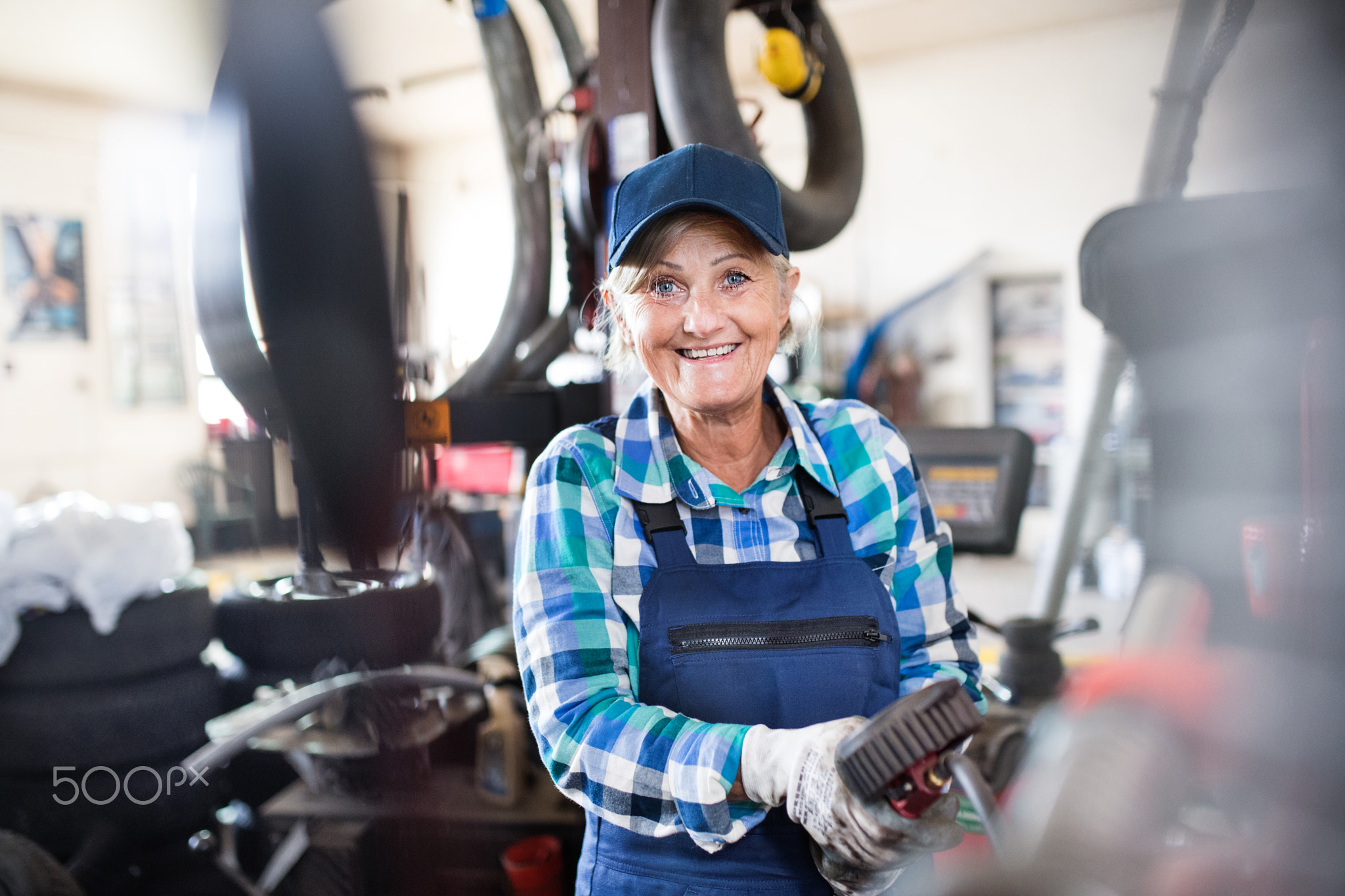 Senior female mechanic repairing a car in a garage.