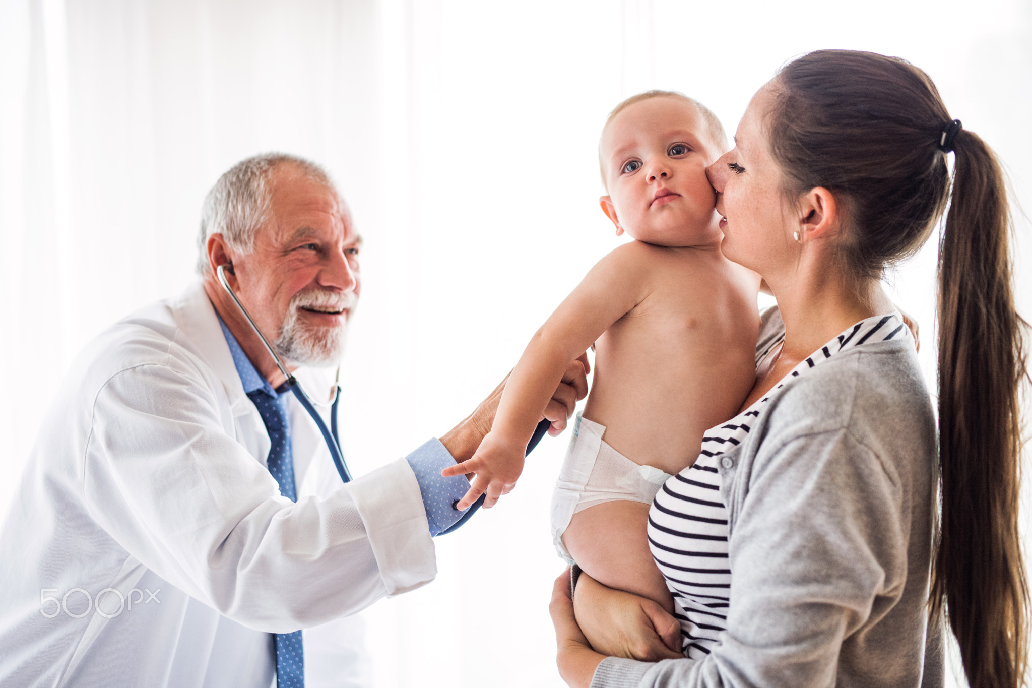 Senior doctor, mother and a baby boy in an office.