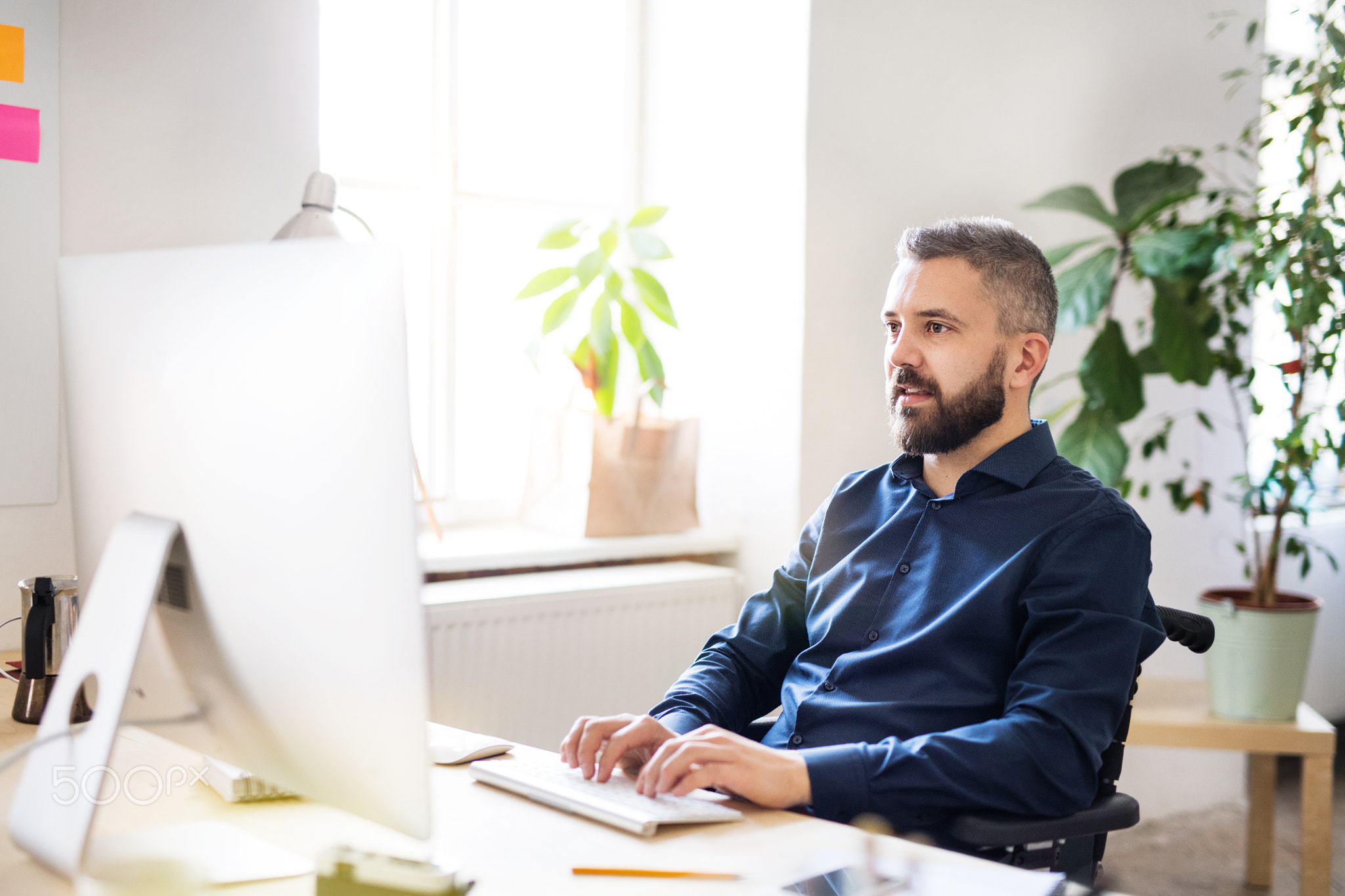 Businessman in wheelchair at the desk in his office.