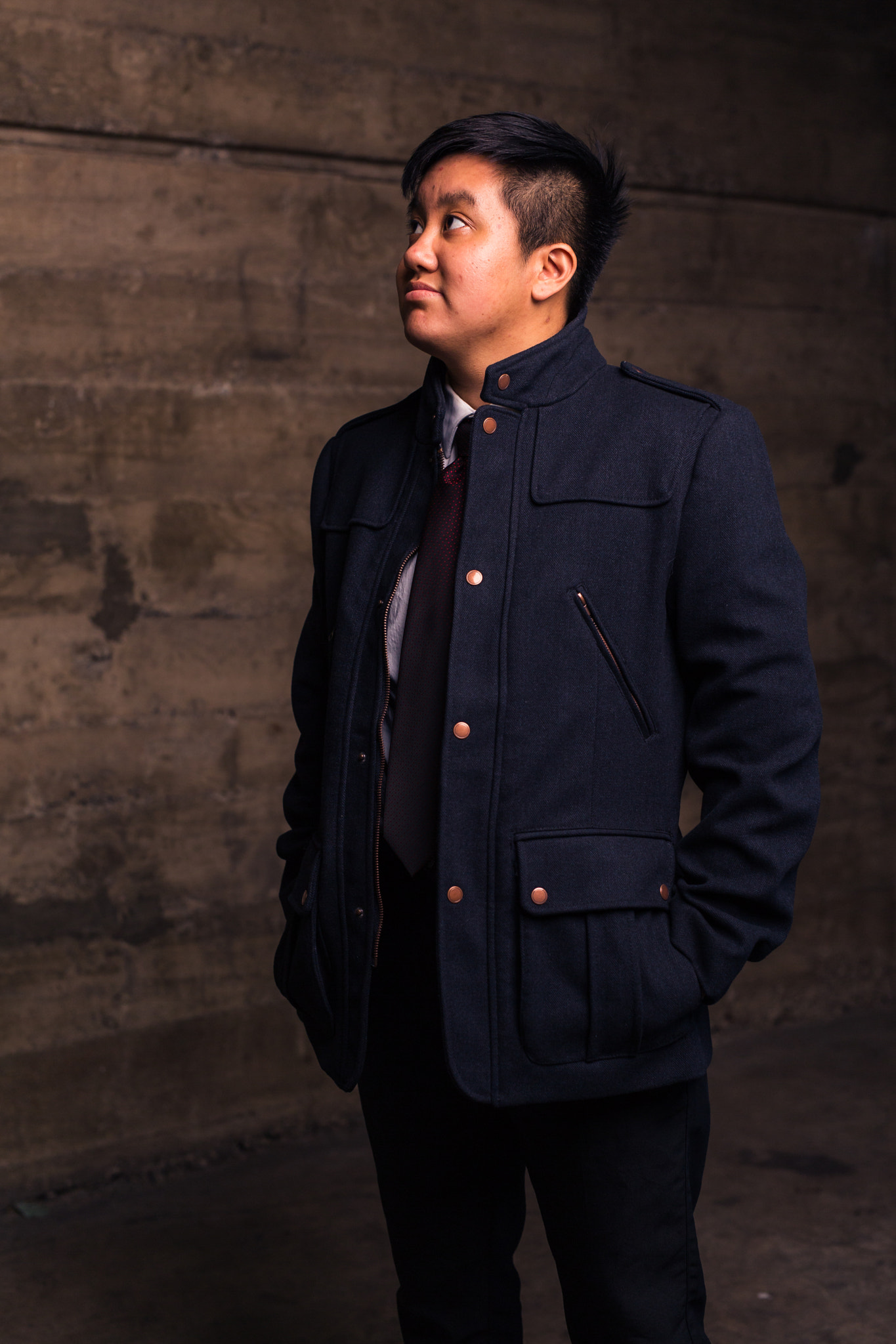 Young transgender man in formal clothing poses in a grungy urban