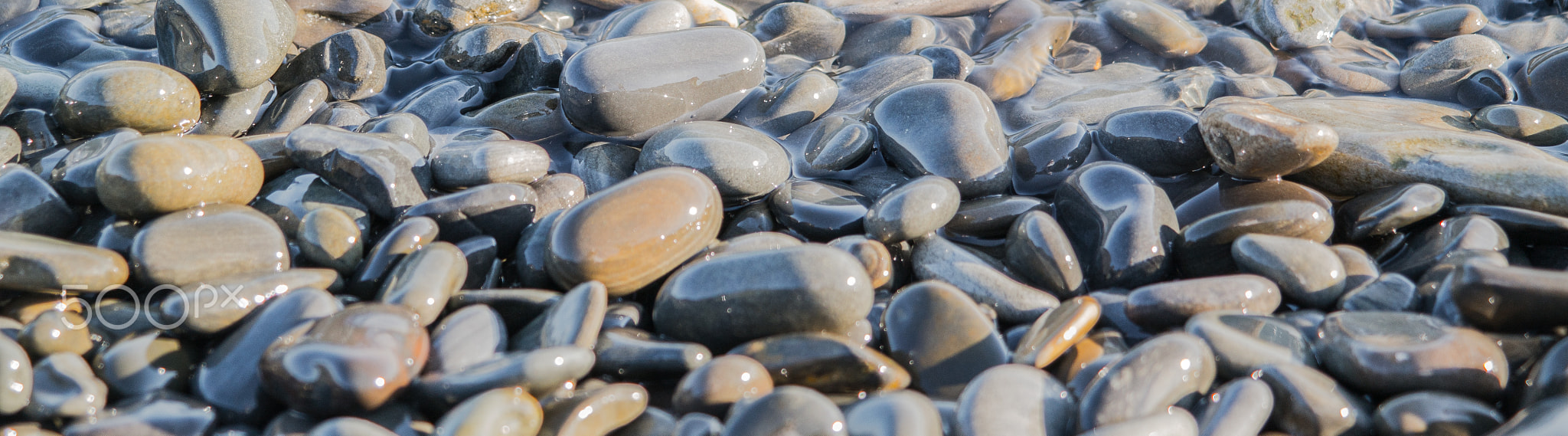 Wet stones on the sea shore suitable for header or footer