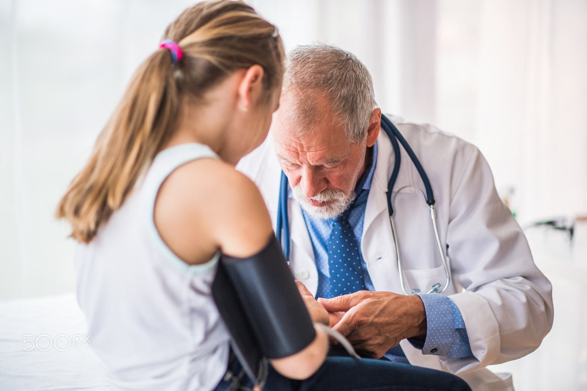 Senior doctor checking a small girl in his office.