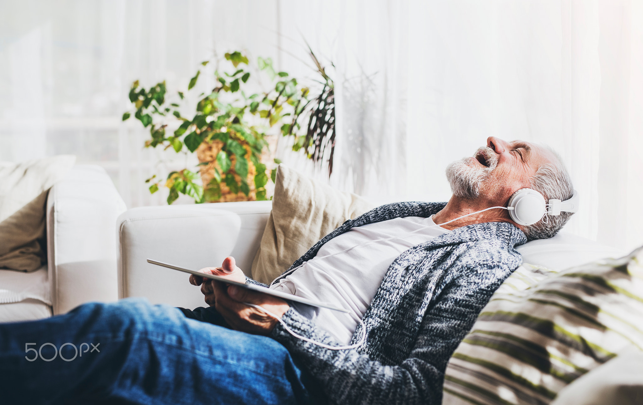 Senior man with tablet relaxing at home.