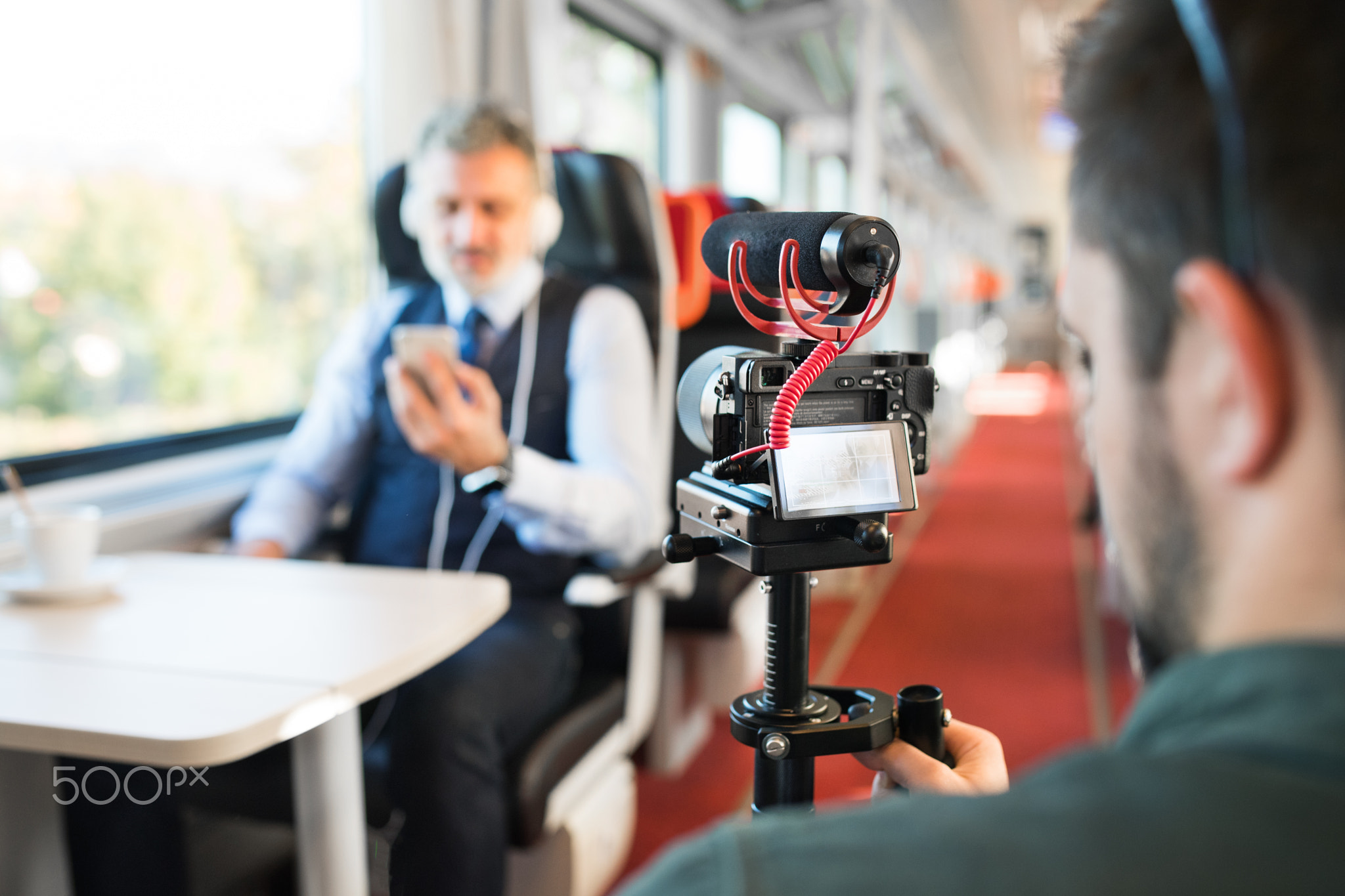 Mature businessman with smartphone travelling by train.