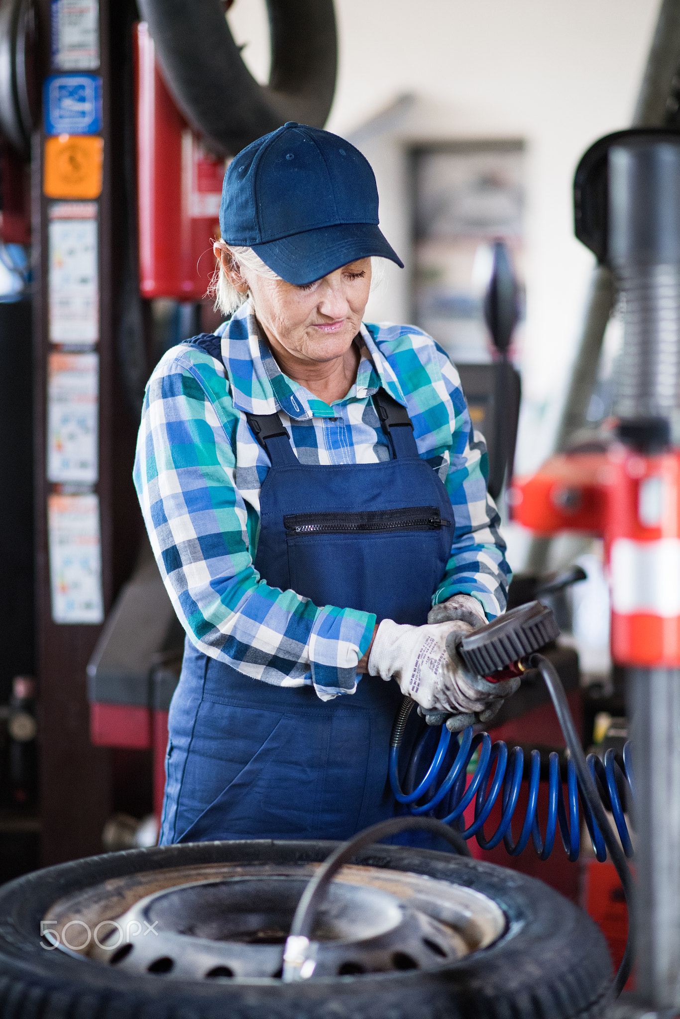 Senior female mechanic repairing a car in a garage.