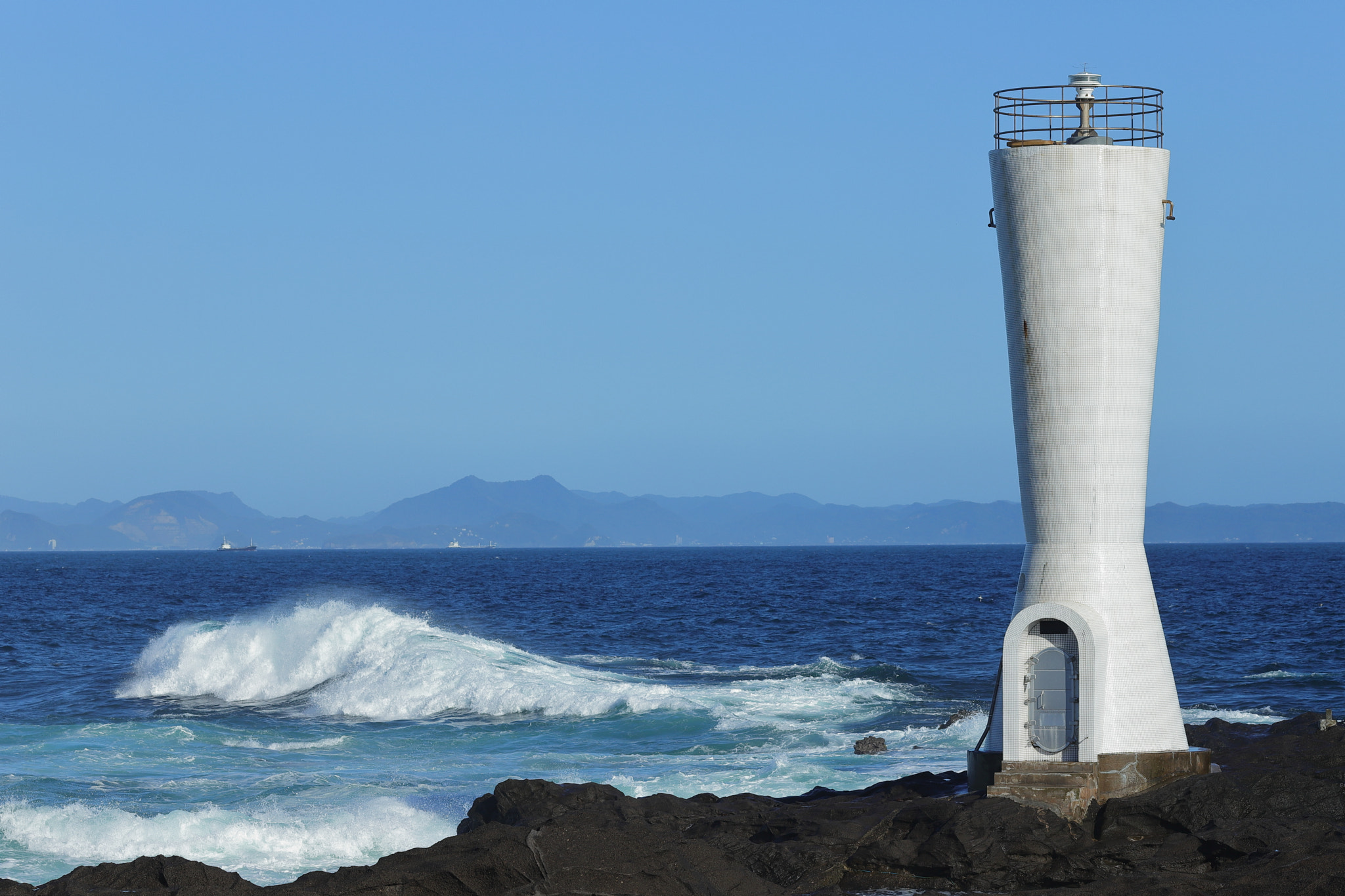 Canon EF 135mm F2L USM sample photo. A lighthouse beside a blue ocean photography