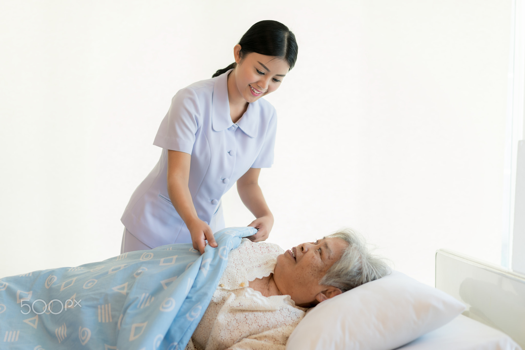 Asian nurse in elderly care cover her with a blanket for the eld