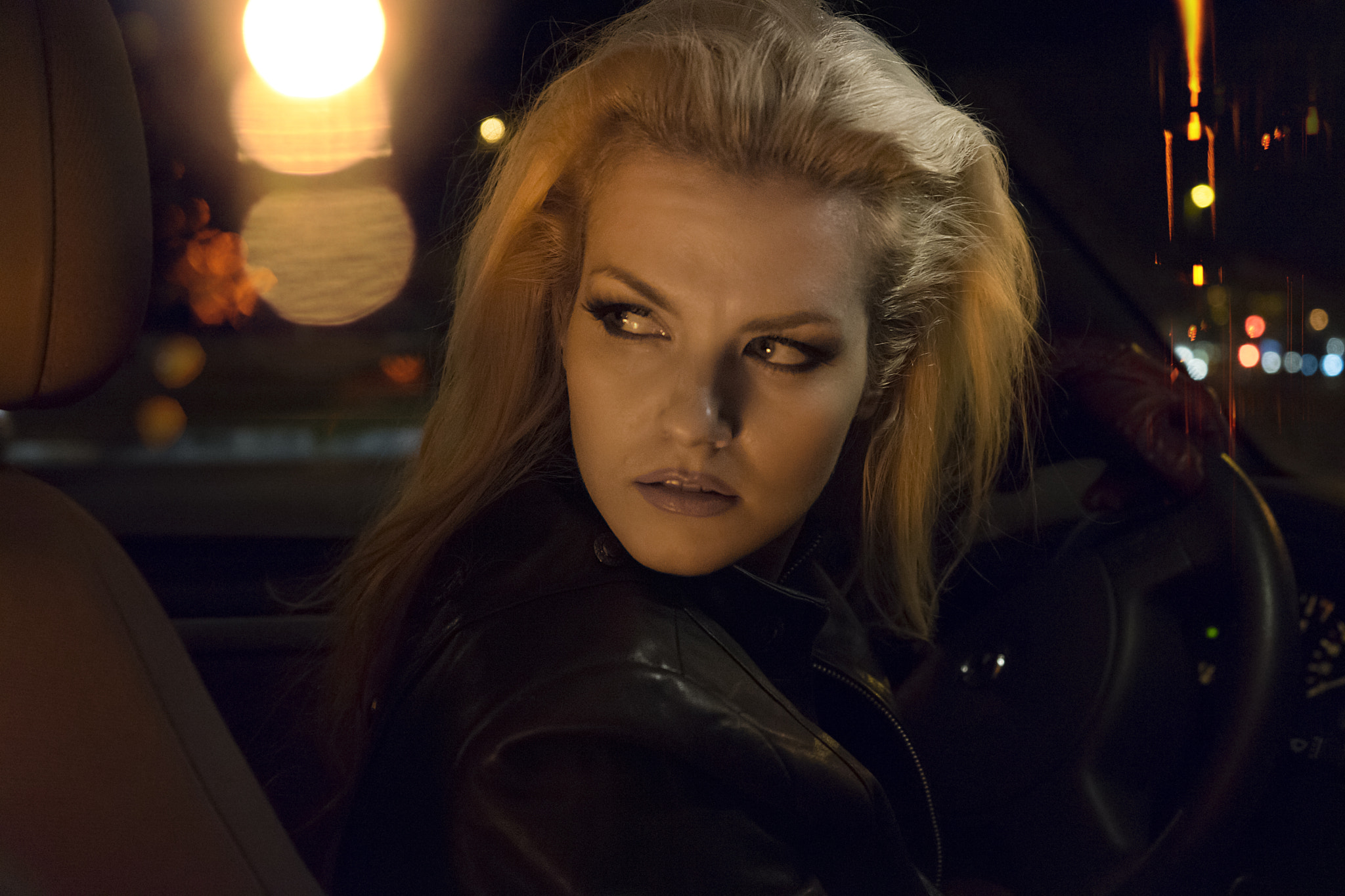 blonde woman in a car at night