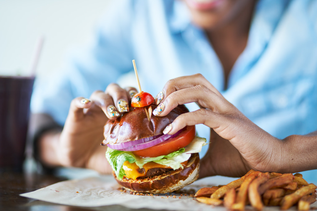 close up of african american woman about to eat vegan meatless cheese burger at restaurant by Joshua Resnick on 500px.com