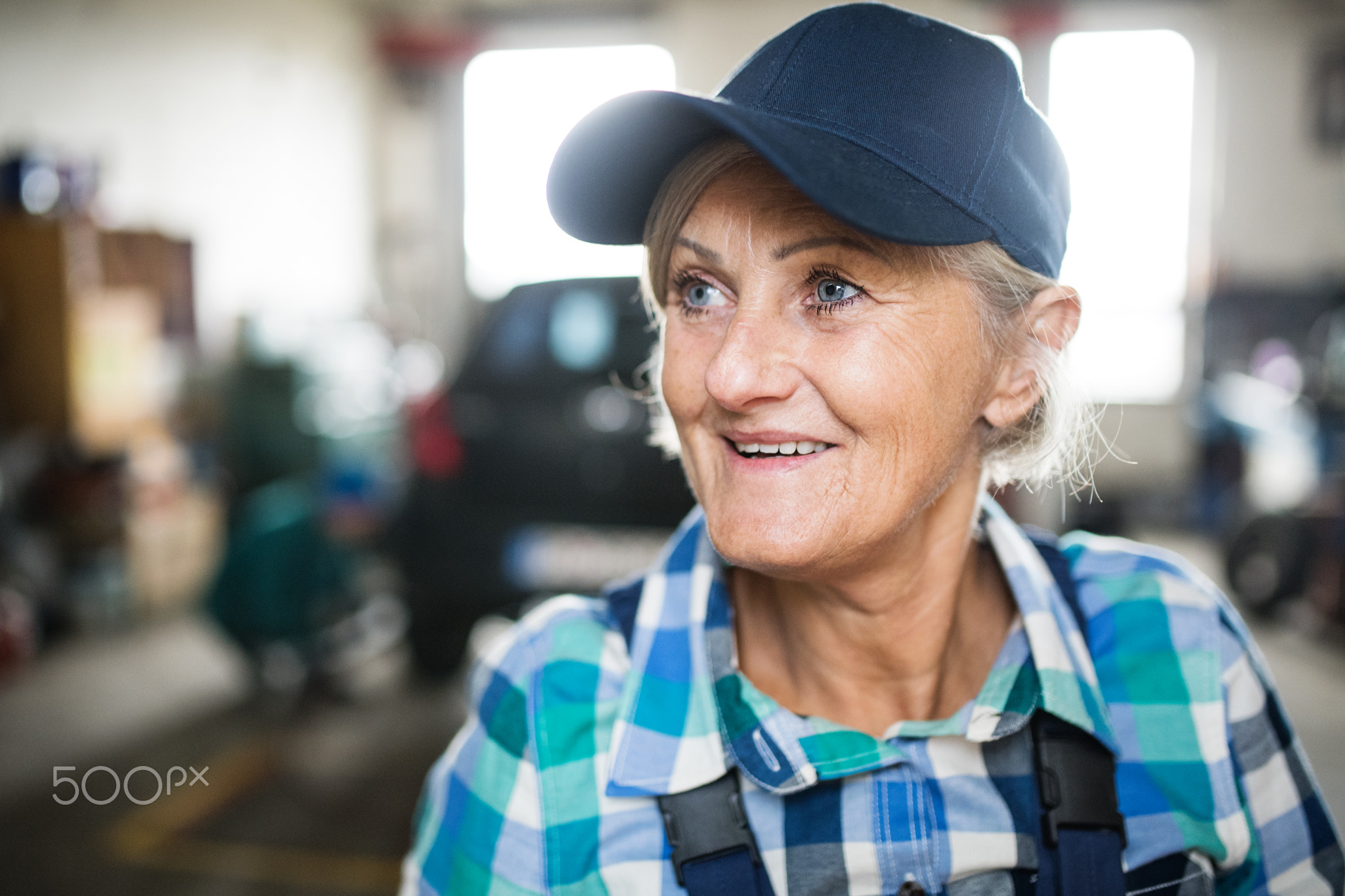 Senior female mechanic repairing a car in a garage.