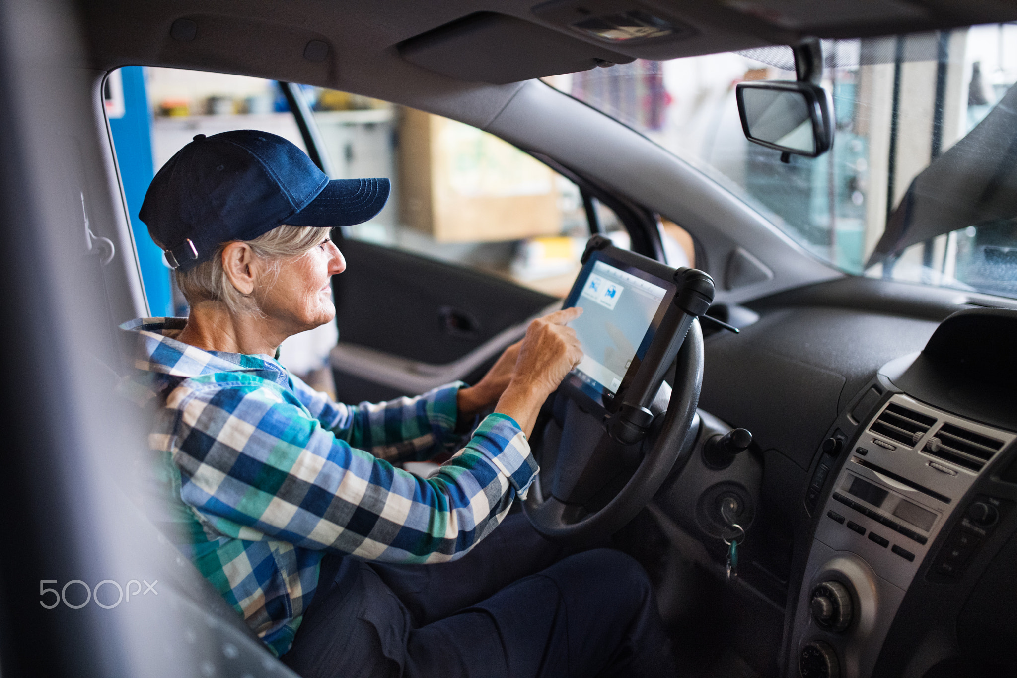 Senior female mechanic repairing a car in a garage.