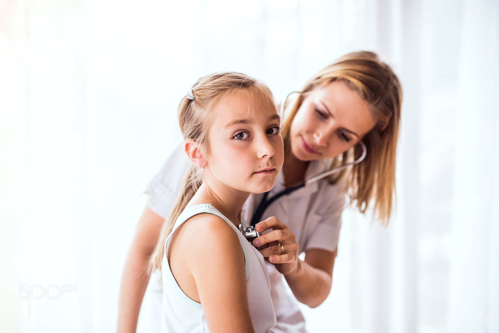 Young female doctor examining a small girl in her office.