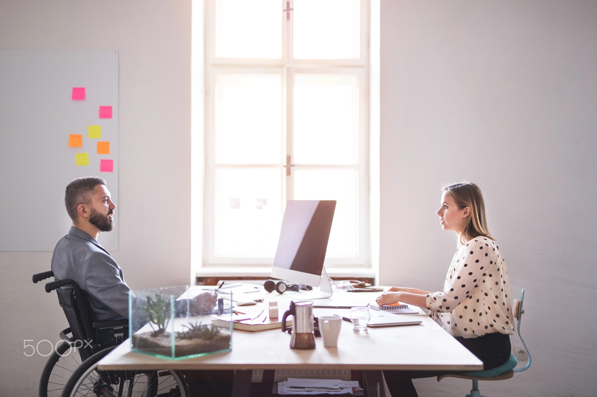 Two business people with wheelchair in the office.