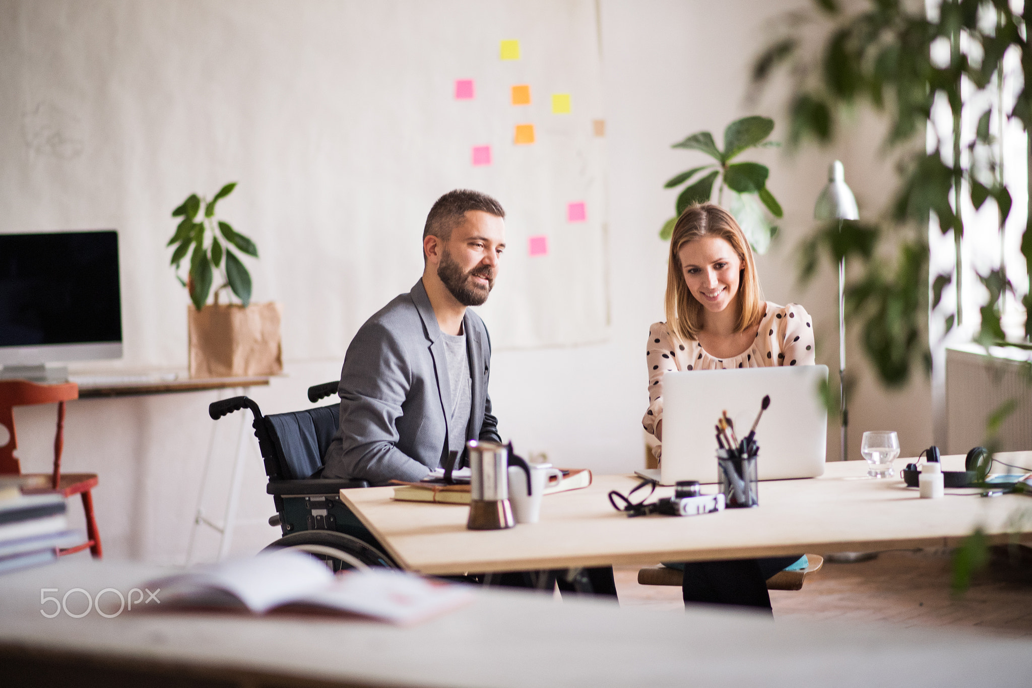 Two business people with wheelchair in the office.