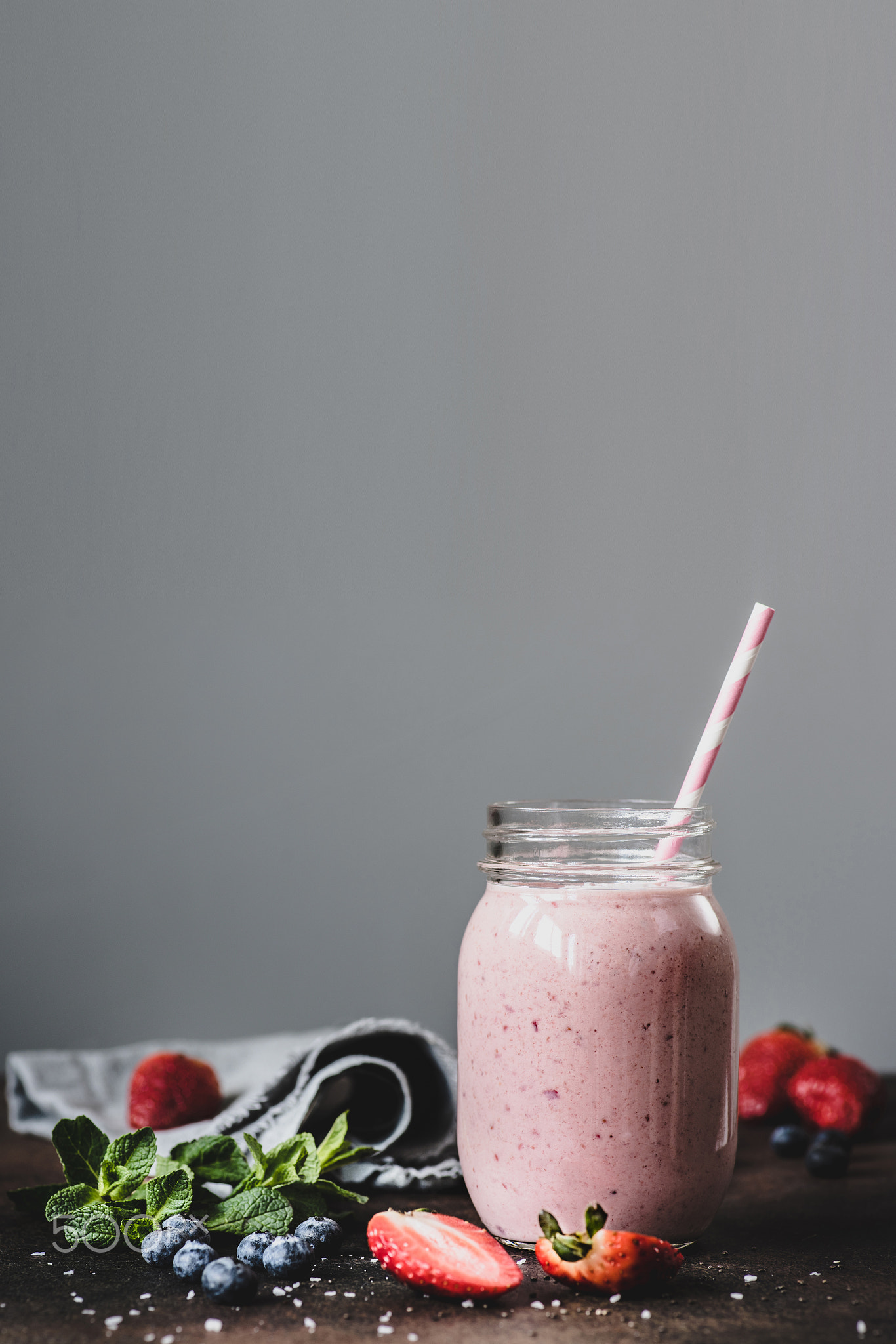 Pink strawbery smoothie in jar with drinking straw