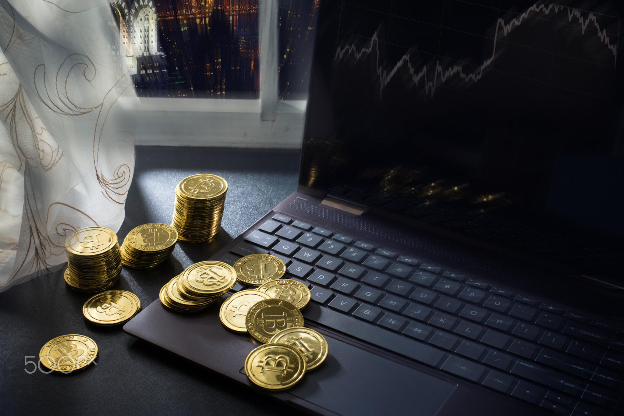 Playing with cryptocurrency: stacks of bitcoins on the table near PC, New York, USA