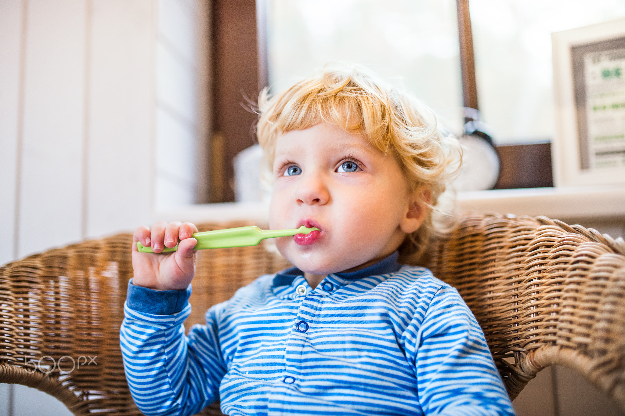 Cute toddler boy brushing his teeth in the bathroom.