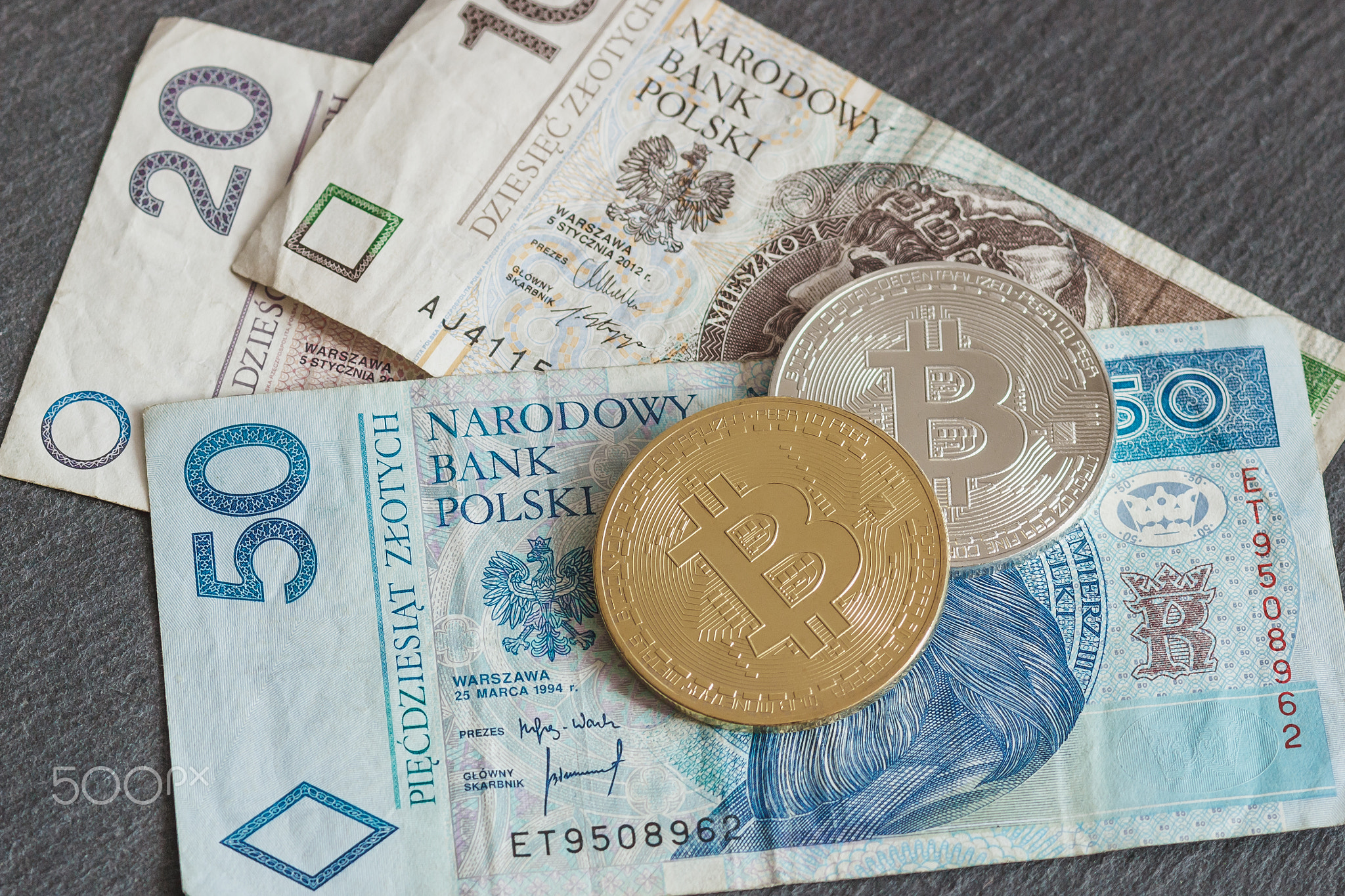 Polish zloty and bitcoins on the black slate stone background