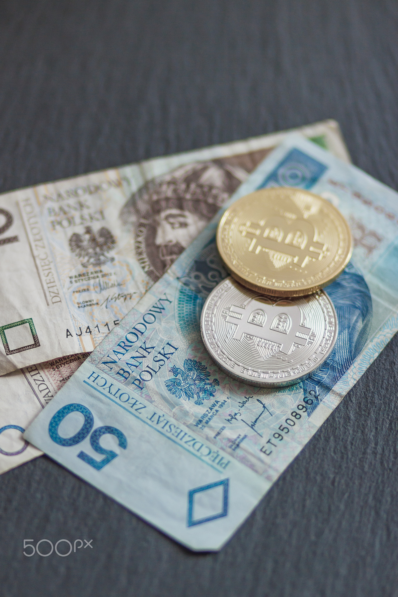 Polish zloty and bitcoins on the black slate stone background