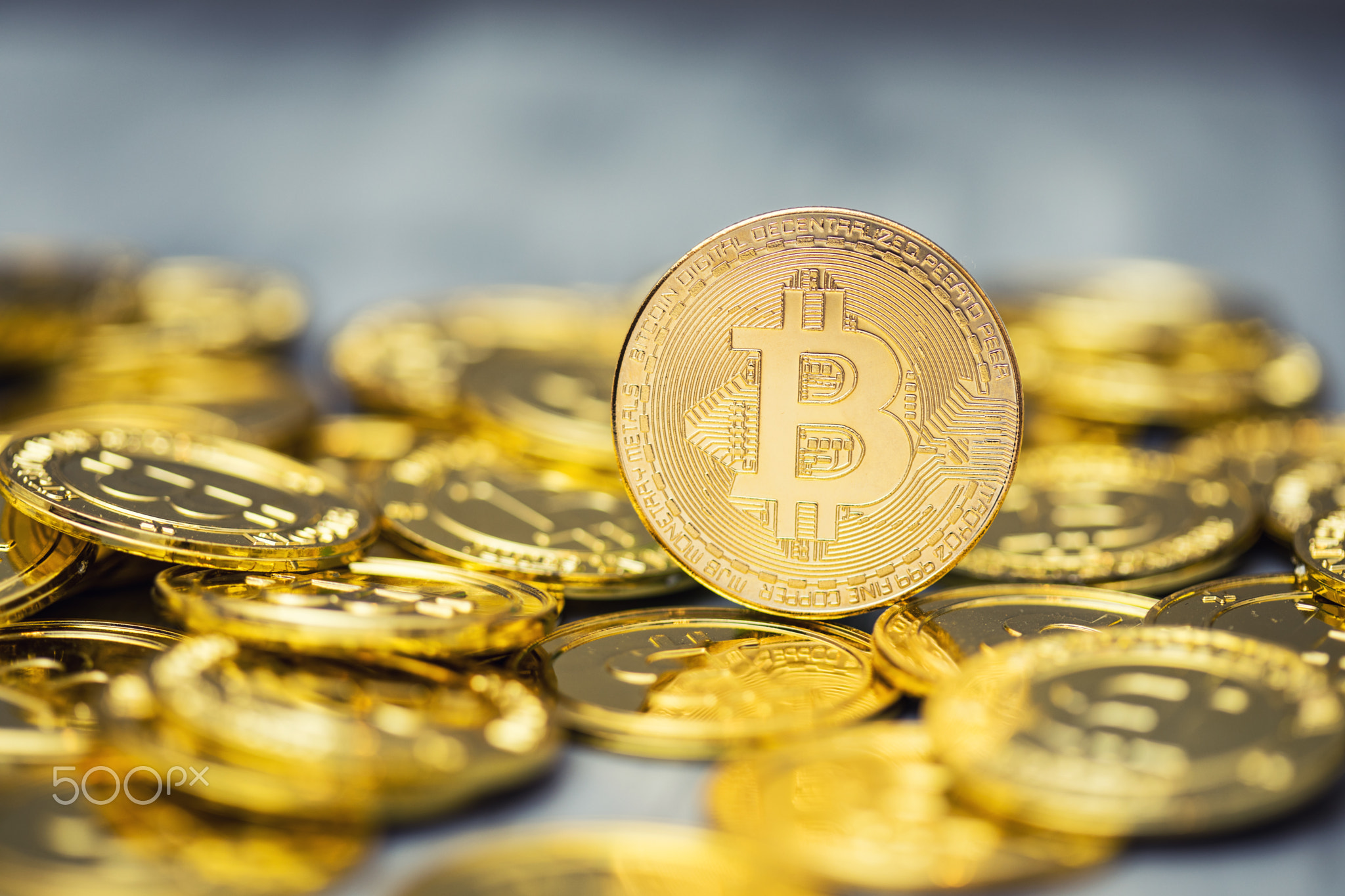 A pile of golden bitcoins on a solid backdrop