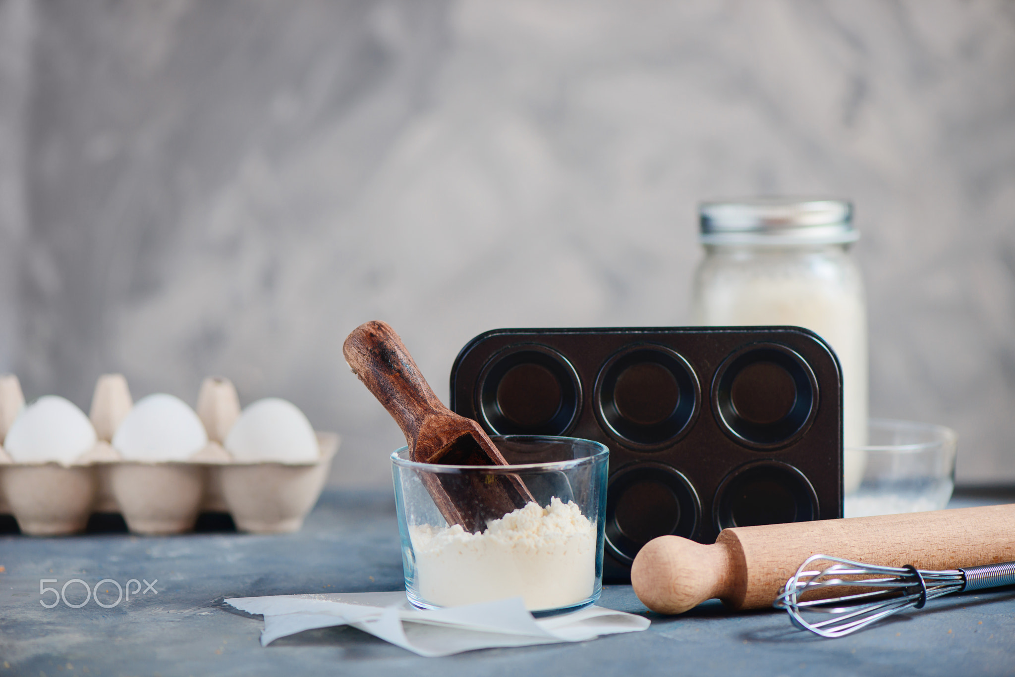 Cooking concept with baking tools and ingredients. Flour scoop, muffin tin, a whisk, a rolling...