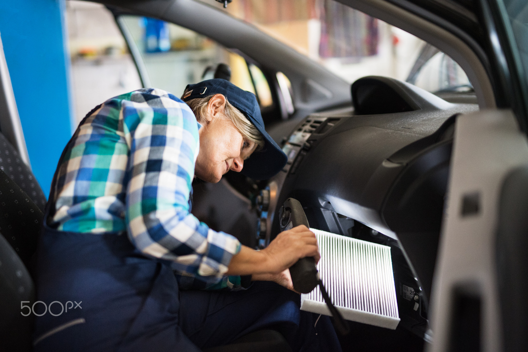 Senior female mechanic repairing a car in a garage.