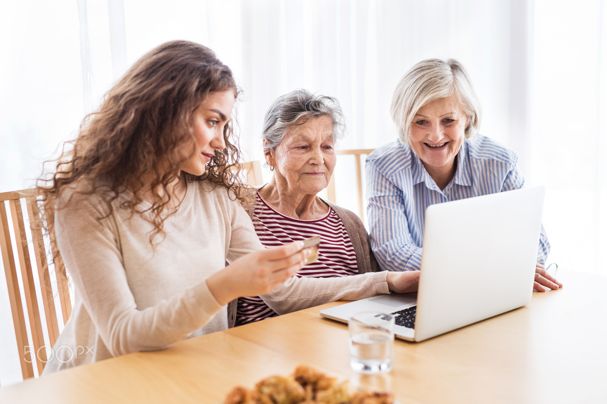 A teenage girl, mother and grandmother with laptop at home.