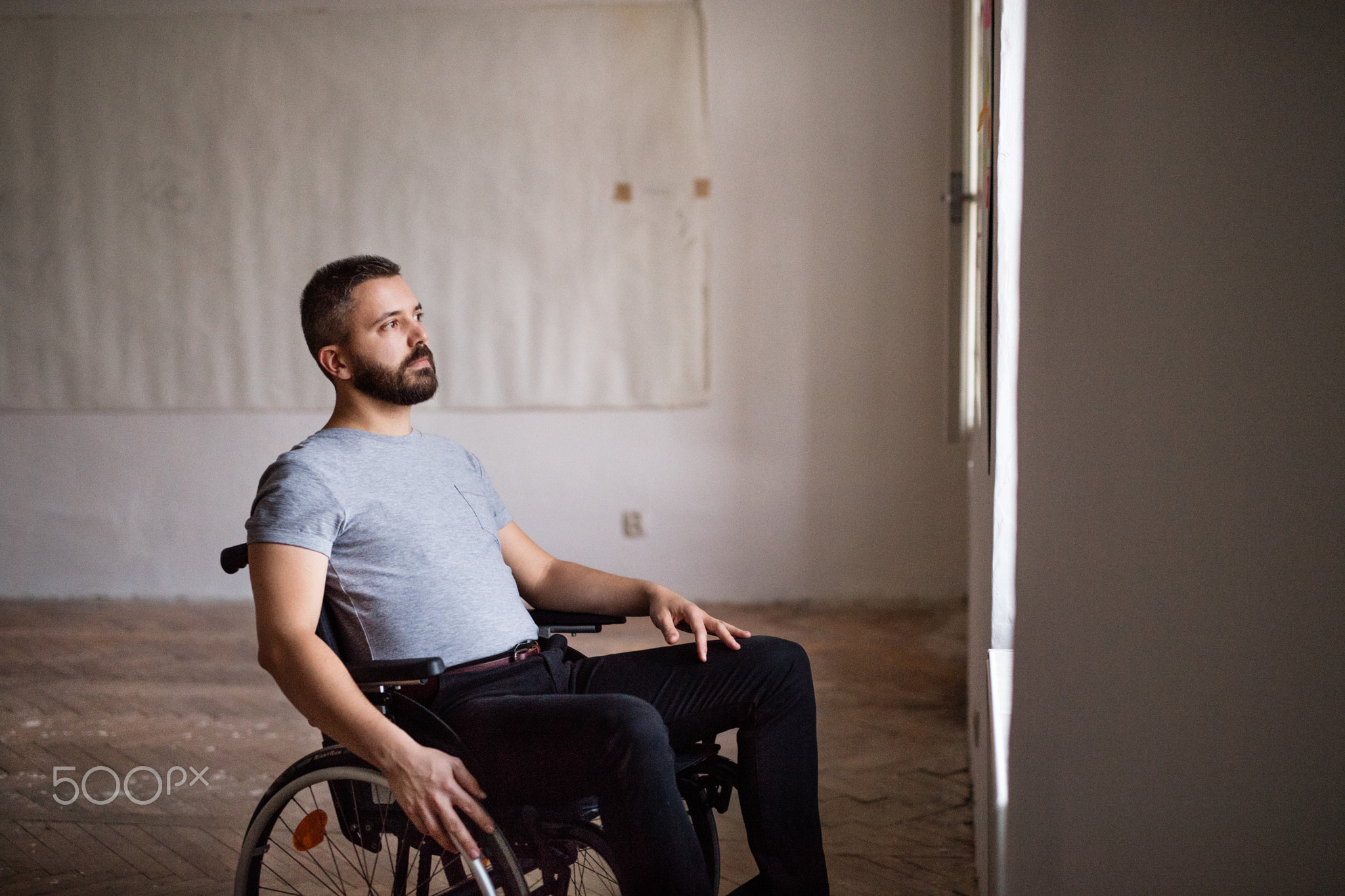 Man in wheelchair looking out of the window.