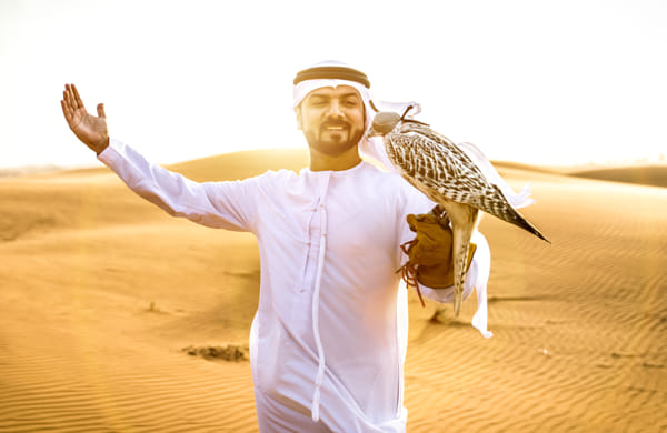 Arabic man with traditional emirates clothes walking in the dese