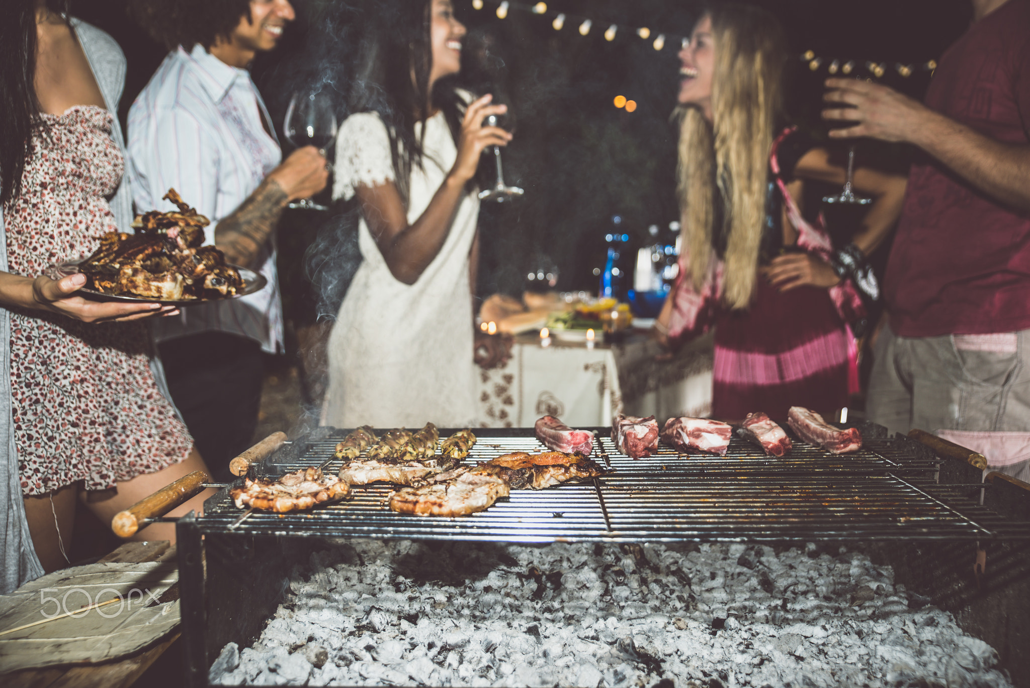 Group of friends making barbecue in the backyard at dinner time