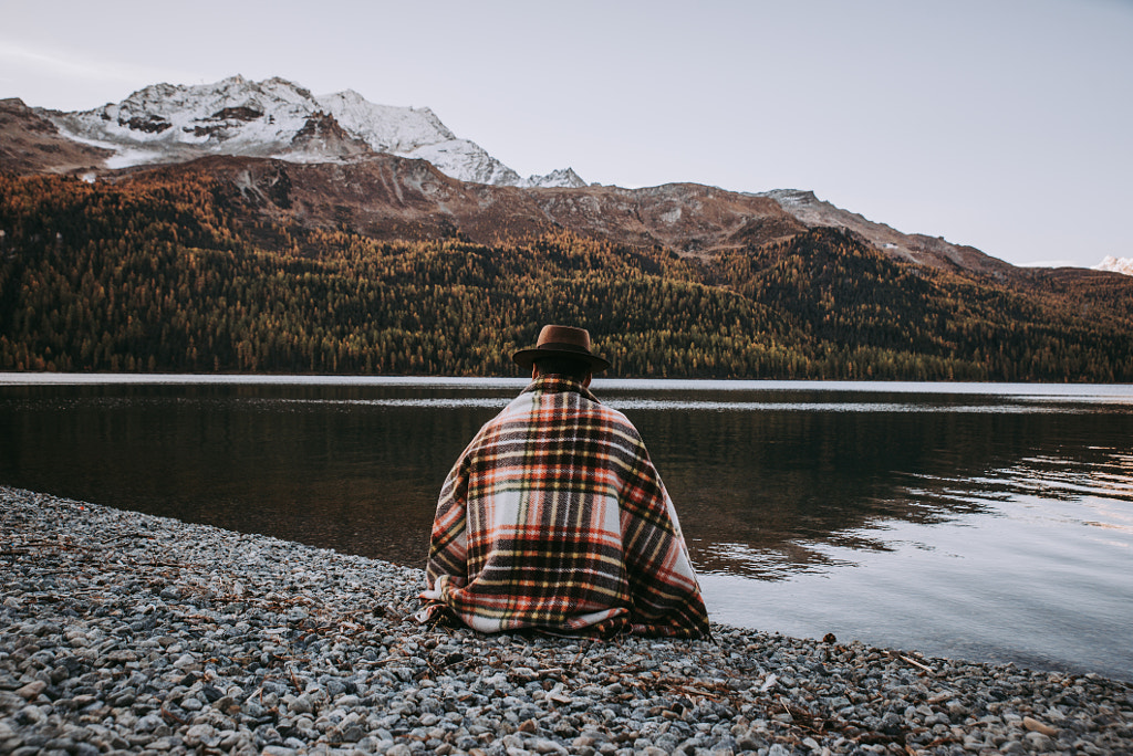 Lonely man enjoying sunrise on a lake beach with mountains backg by Cristian Negroni on 500px.com