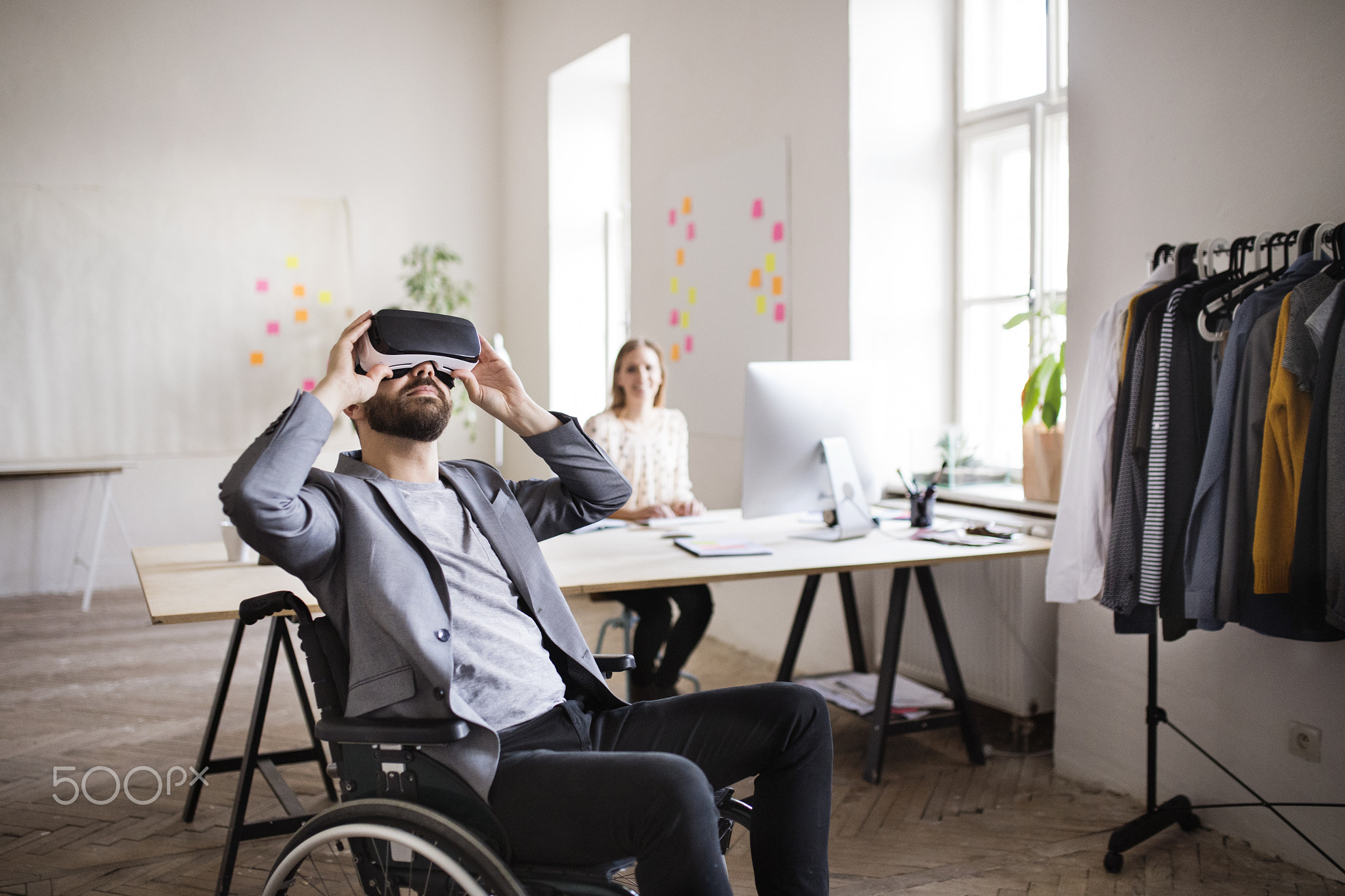 Two business people with wheelchair and VR goggles in the office.