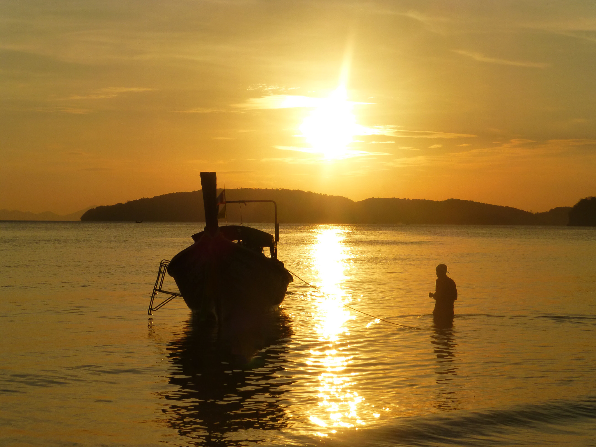 Panasonic Lumix DMC-ZS20 (Lumix DMC-TZ30) sample photo. A man walking into the sea towards a longtail boat at sunset photography