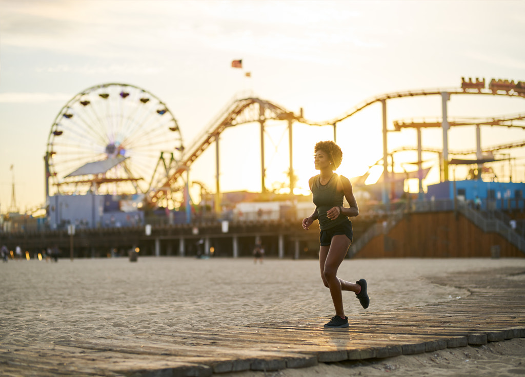 athletic african american woman jogging on boardwalk at sunset by Joshua Resnick on 500px.com