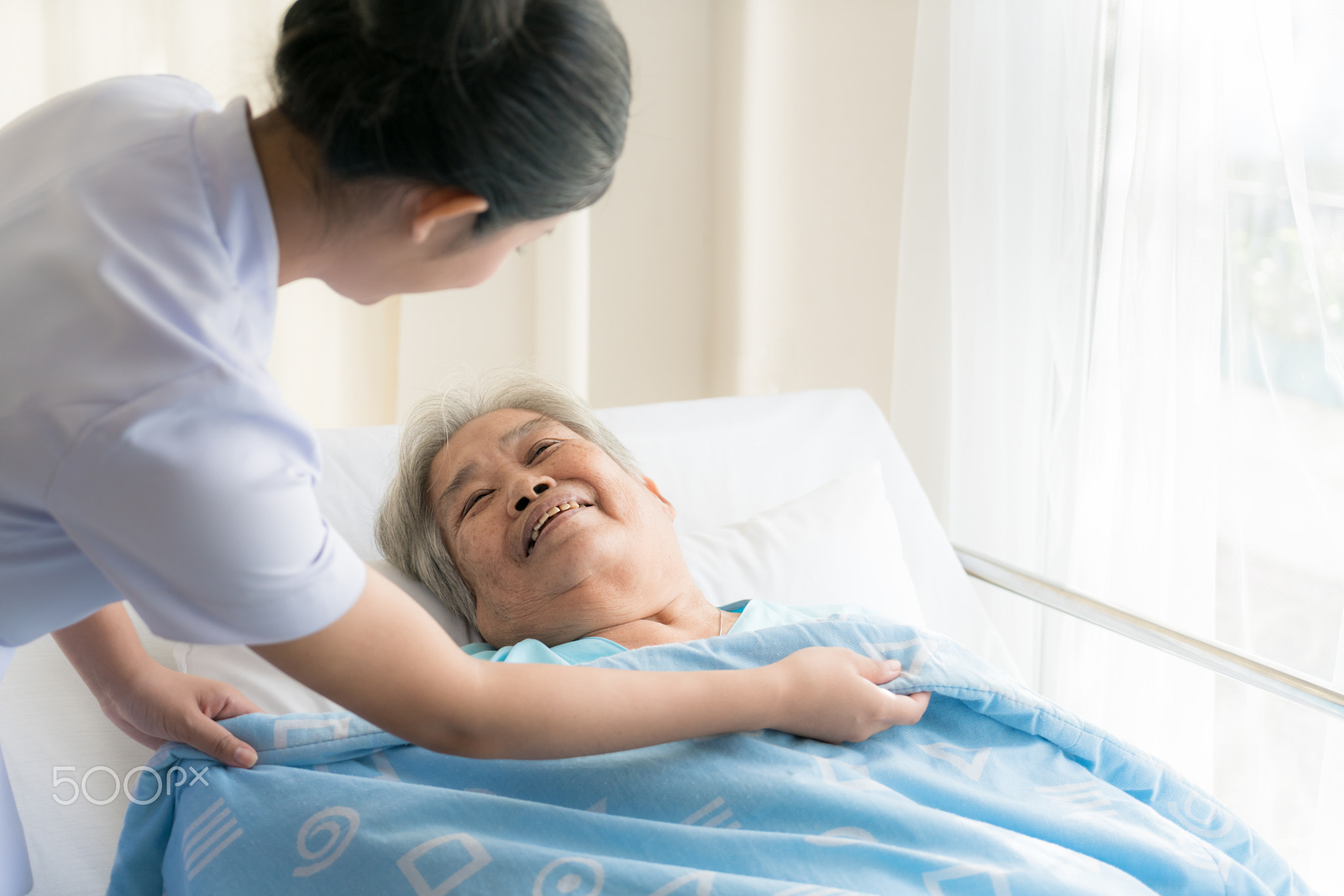 Asian nurse in elderly care cover her with a blanket for the eld