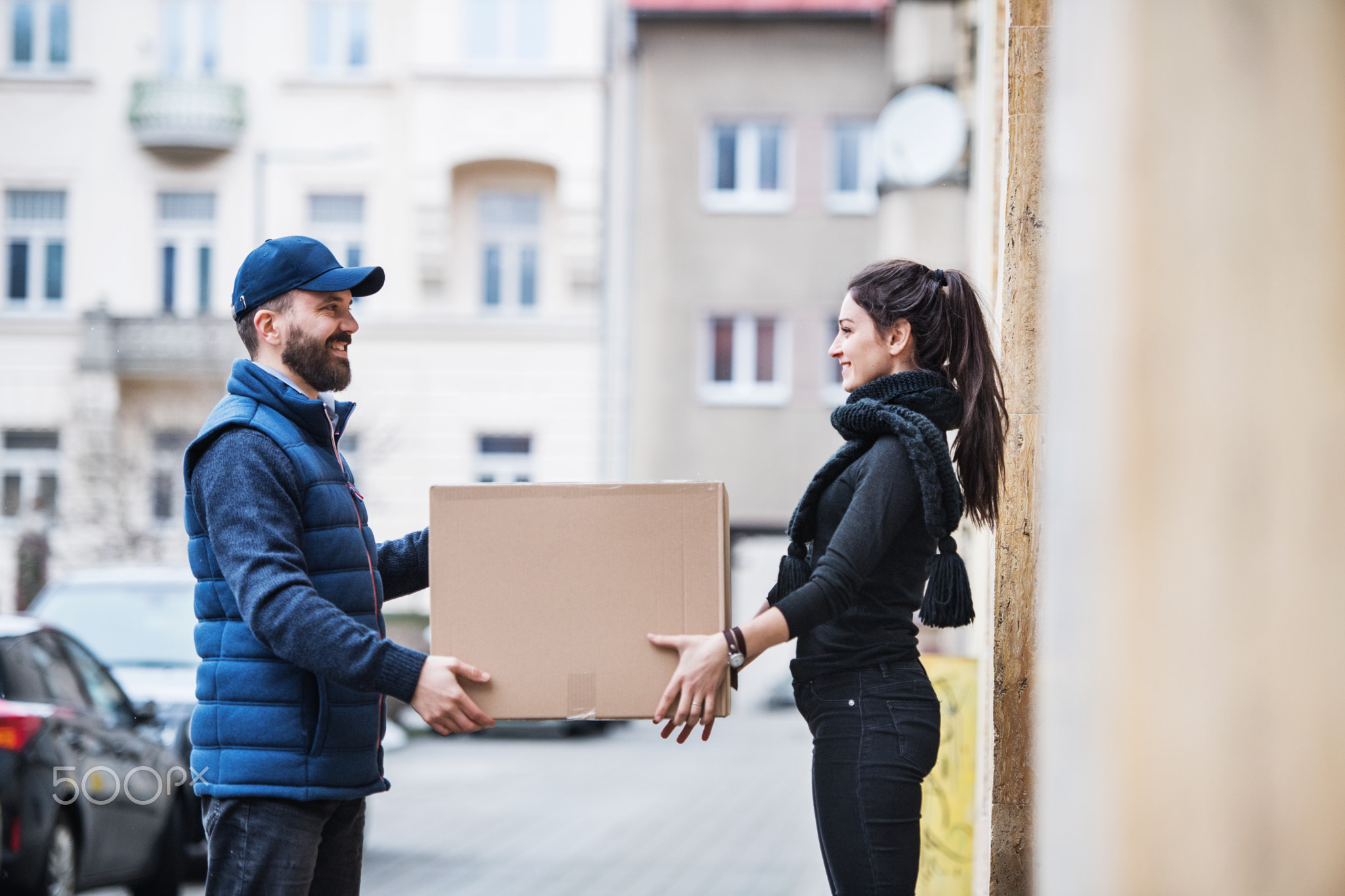 Woman receiving parcel from delivery man at the door.