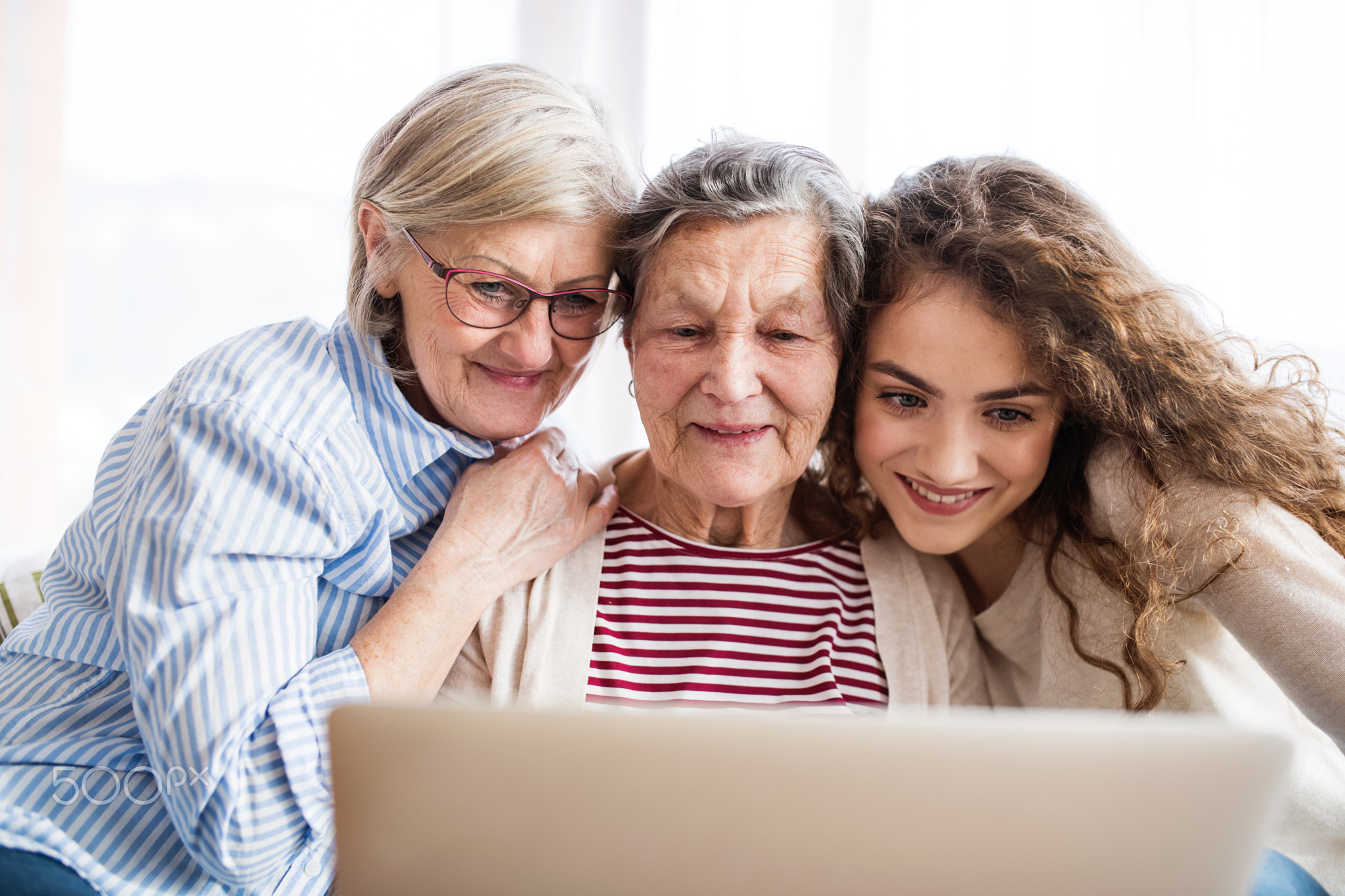 A teenage girl, mother and grandmother with tablet at home.