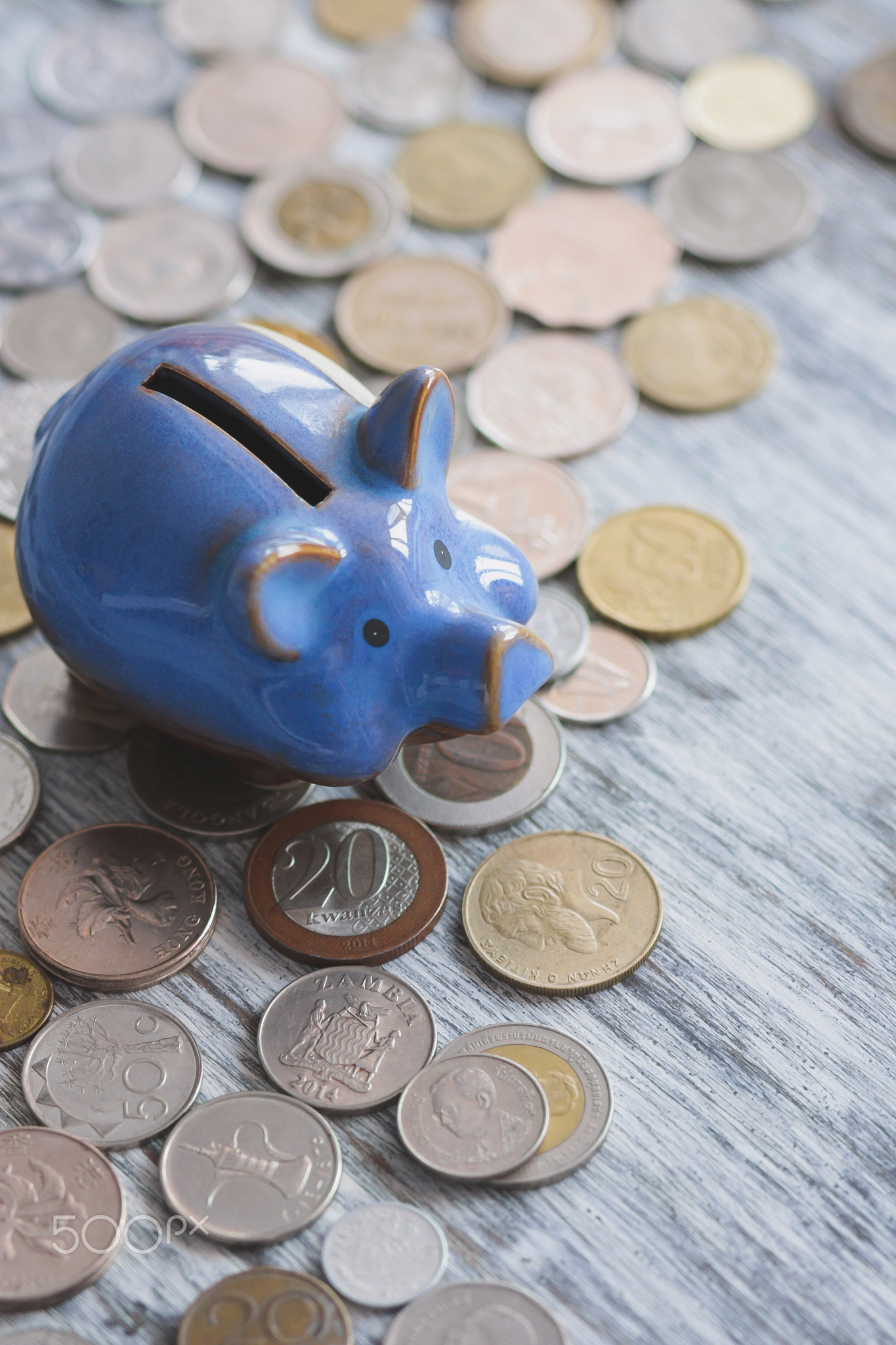 Different collector coins and piggy bank on the wooden background