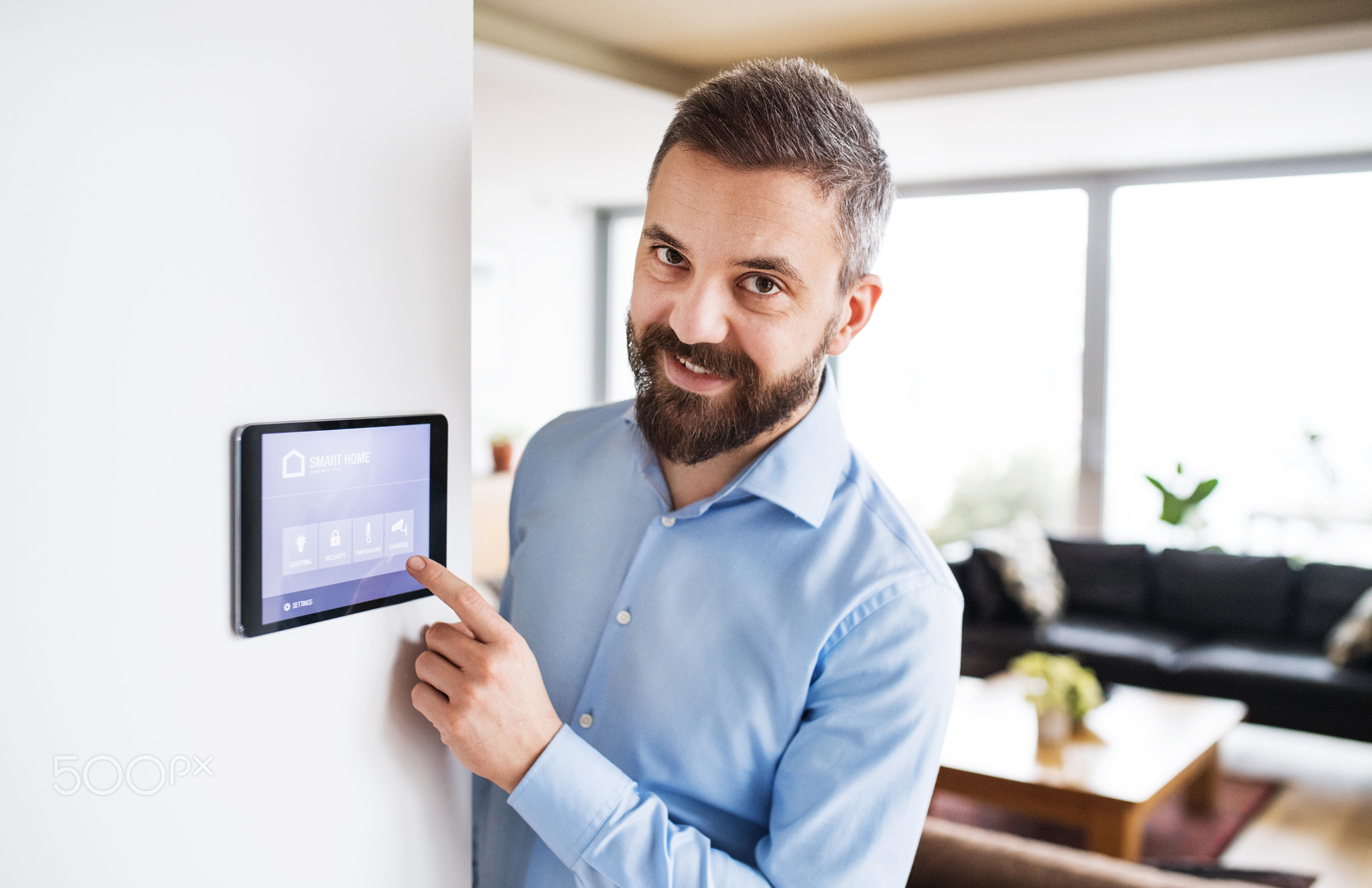 A man pointing to a tablet with smart home screen.