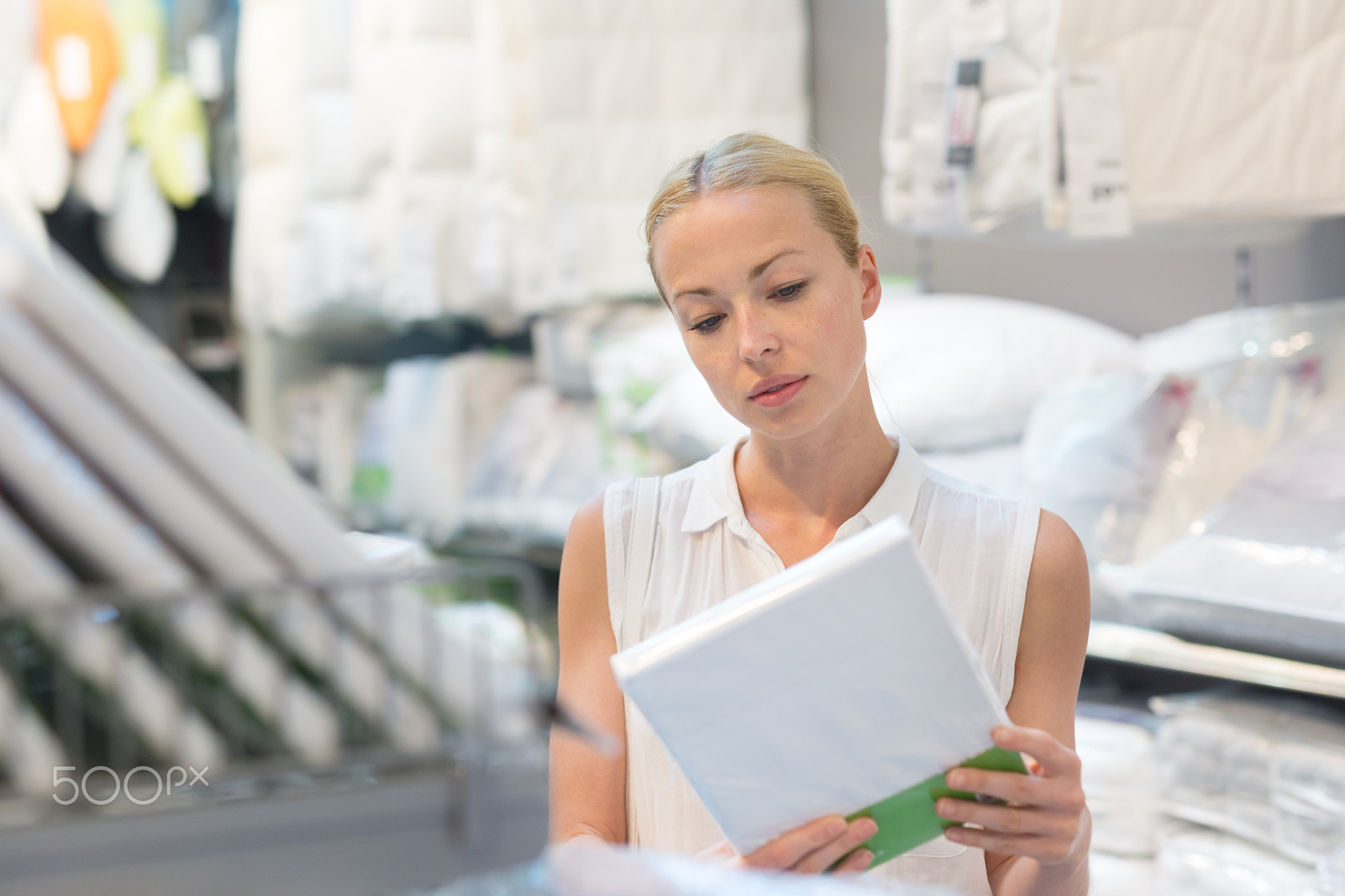 Woman buying bed sheets for her bed in modern home furnishings store.