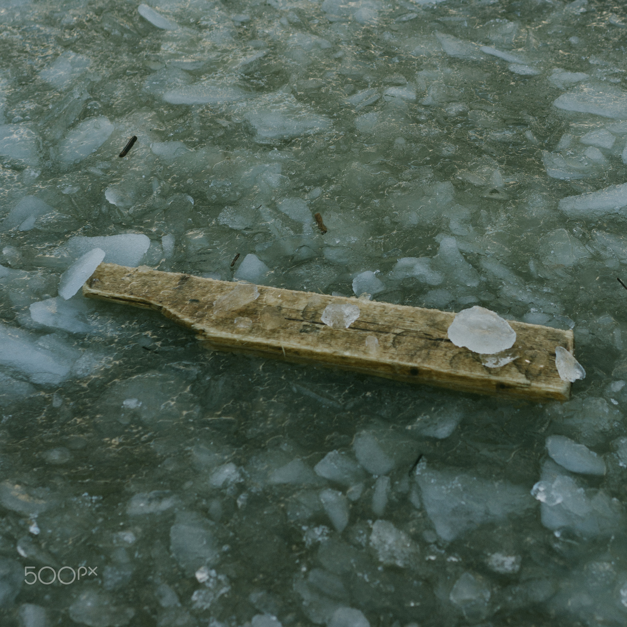 Old timber desk is clutched between ice. Picture is in dark depressive colors. Water is frozen...