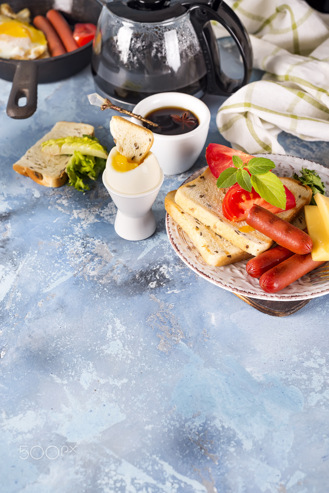 English breakfast. Fried eggs, sausages, toasts, tomatoes on stone table.