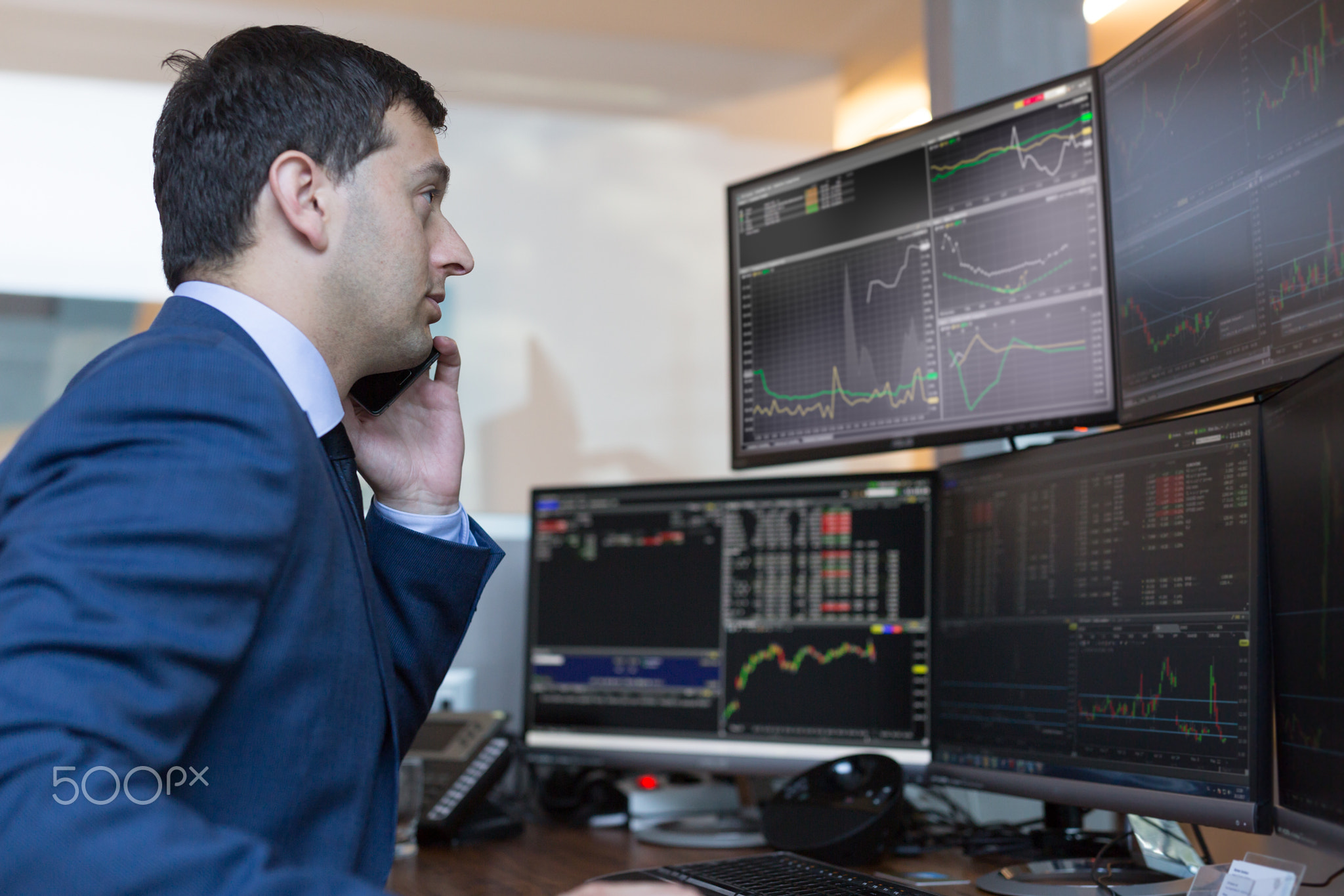 Stock broker trading online watching charts and data analyses on multiple computer screens.