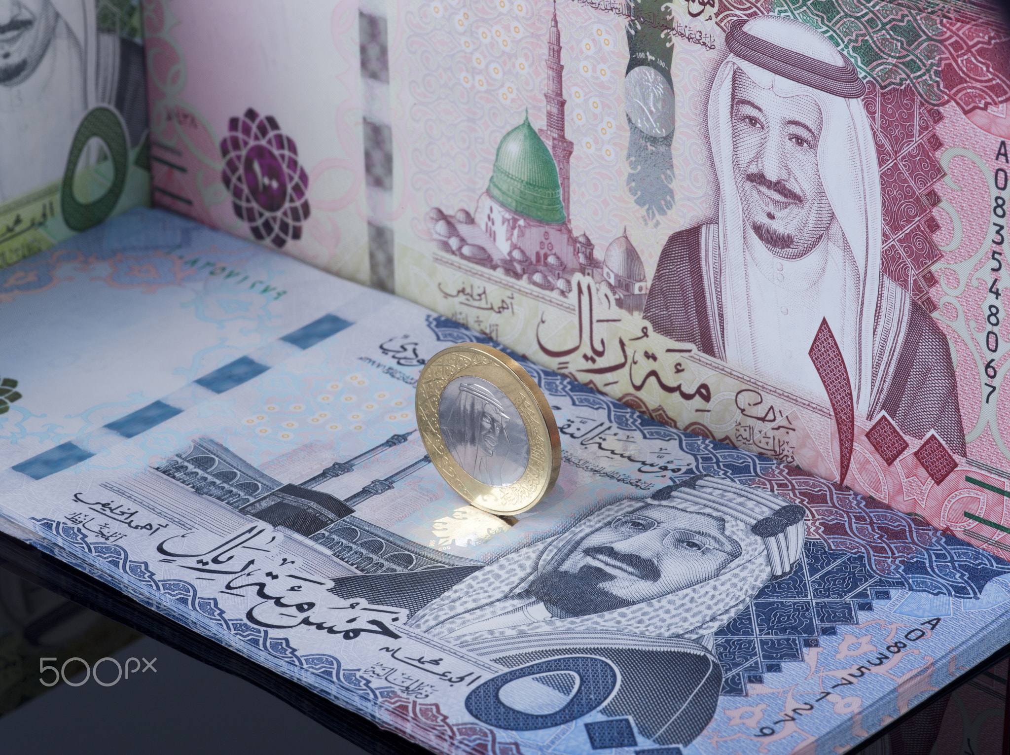 Saudi Riyal Coin Standing on Top of Banknotes