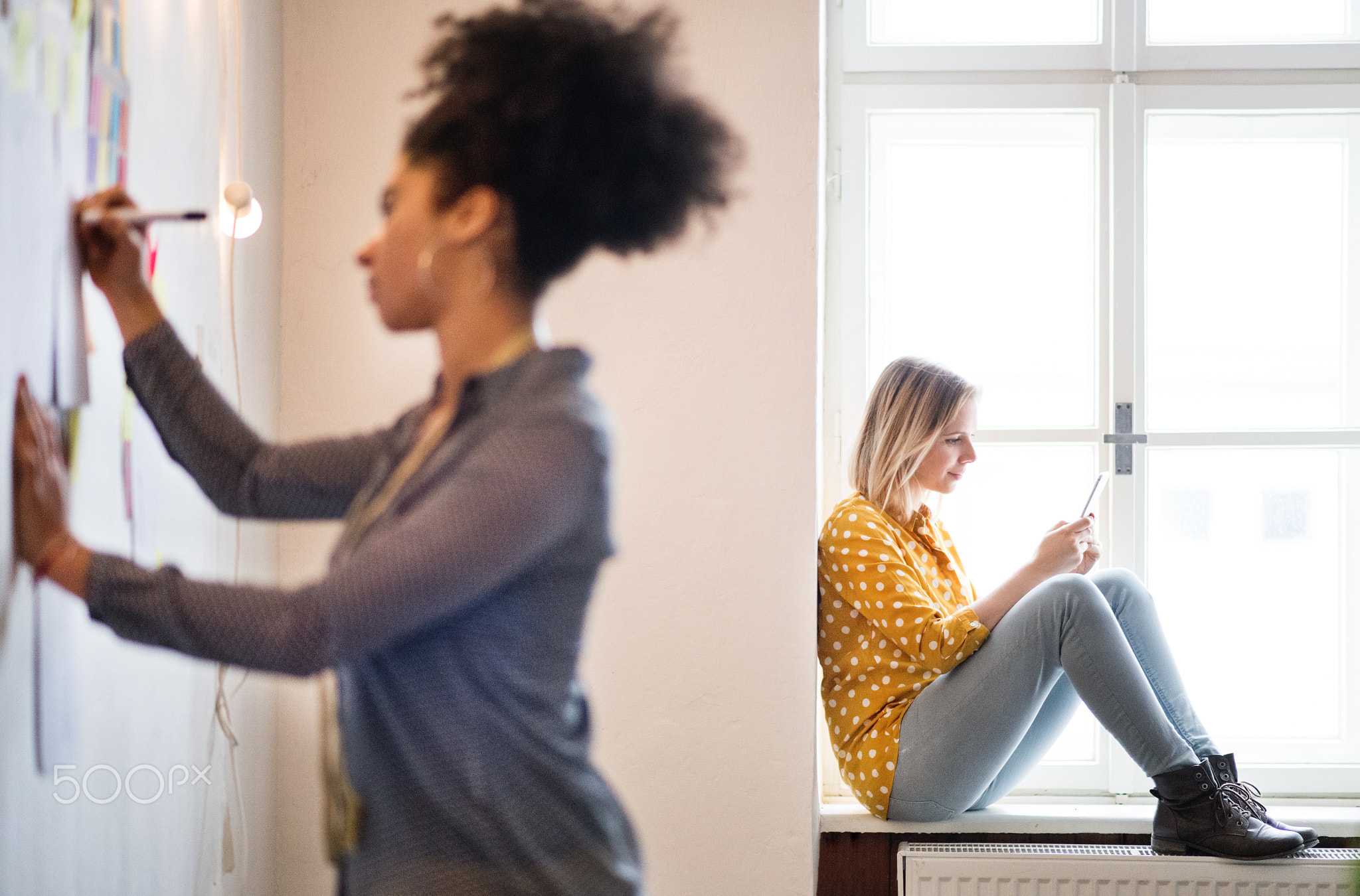 Young creative women with smartphone in studio, startup business.