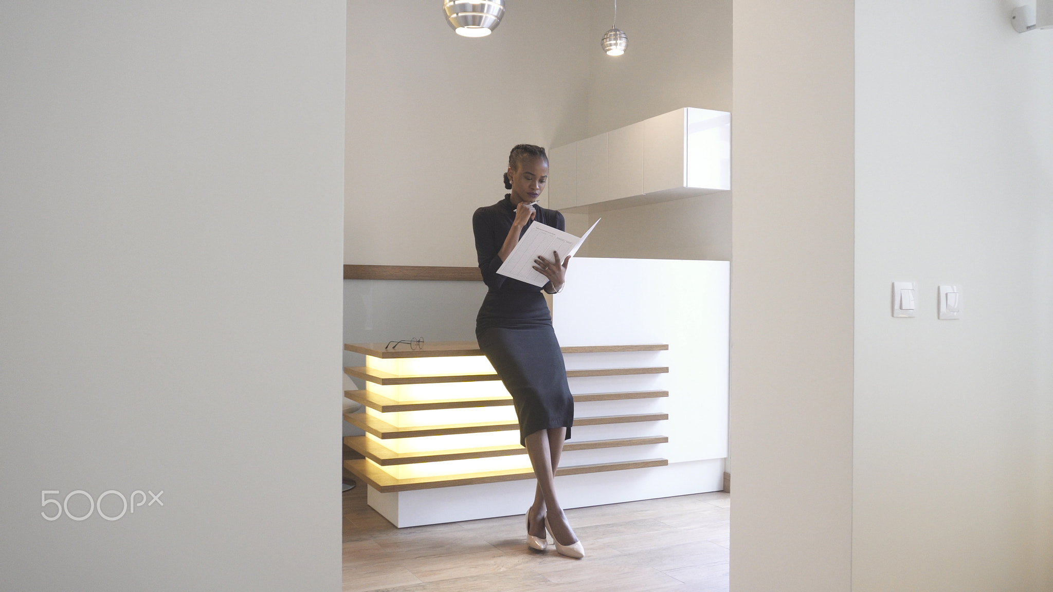 Thoughtful charming afro-american girl with natural make-up at the reception is reading the...